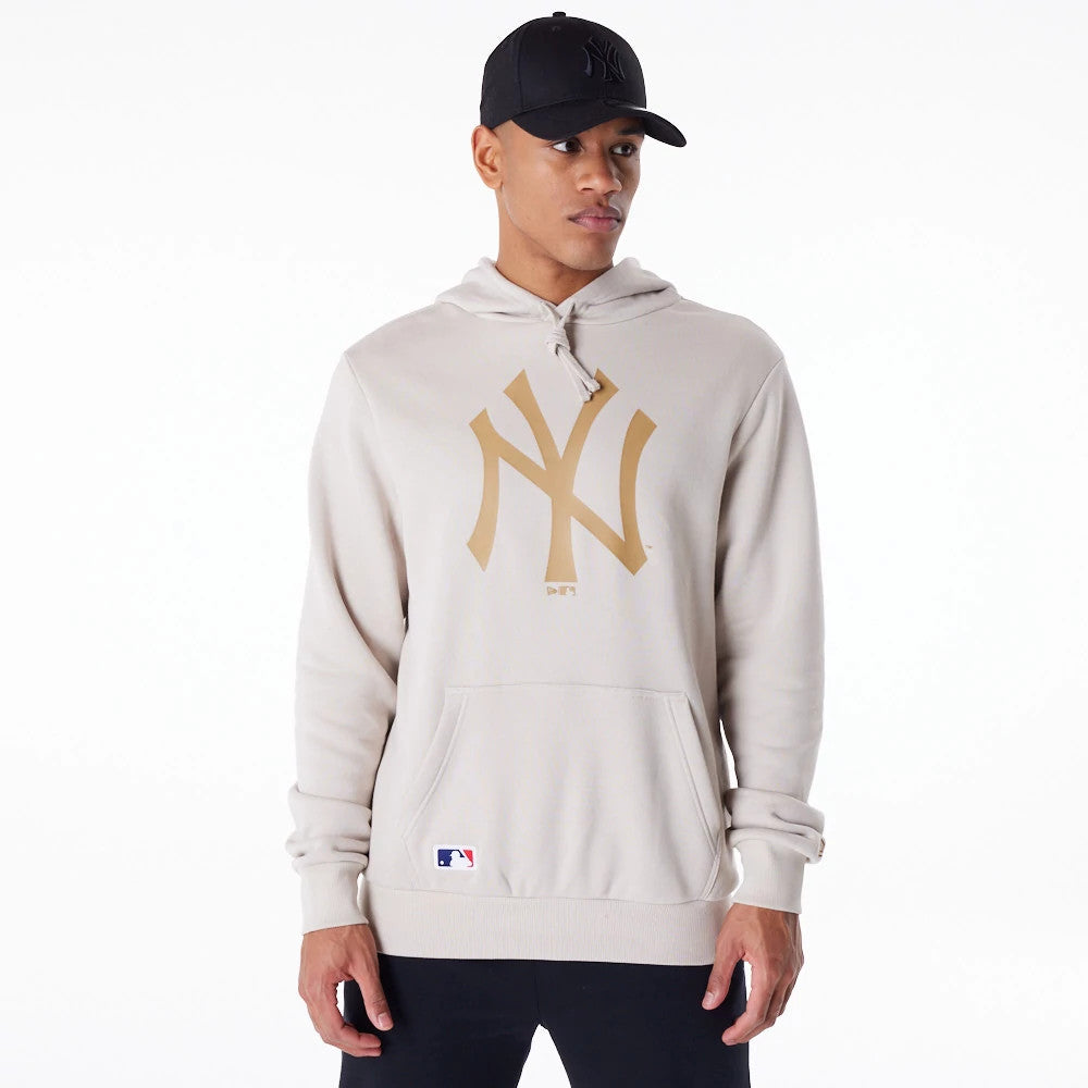 New York Yankees MLB Regular Light Beige Pullover Hoodie, on-model view showing a large beige "NY" logo embossed on the front, with drawstrings at the hood and a small MLB logo stitched near the left pocket.