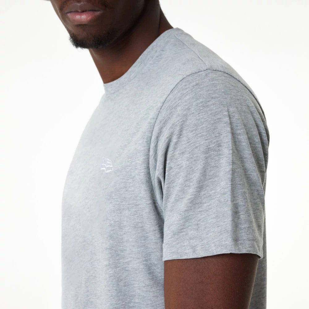New Era Essential Grey T-Shirt, side view showing the light grey fabric with a raised New Era logo embroidered in white on the left chest area, featuring a classic short sleeve design.