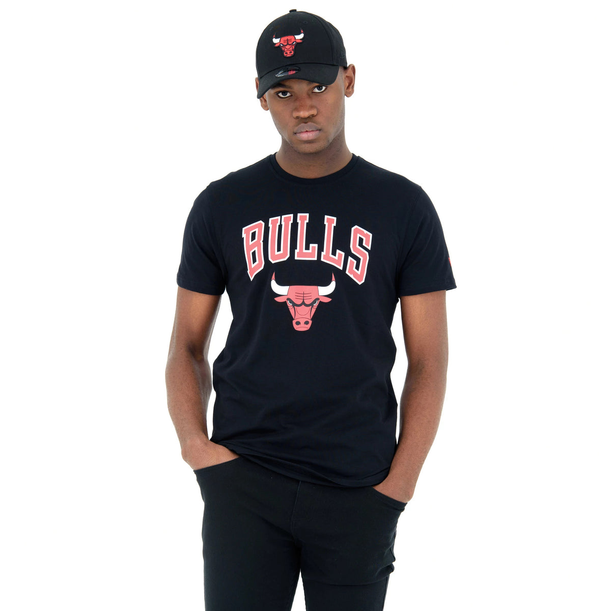 Chicago Bulls NBA Regular Black T-Shirt, front view showing the black shirt with a red and white Bulls logo and text centred on the chest, worn by a person also wearing a black cap with a matching embossed Bulls logo.
