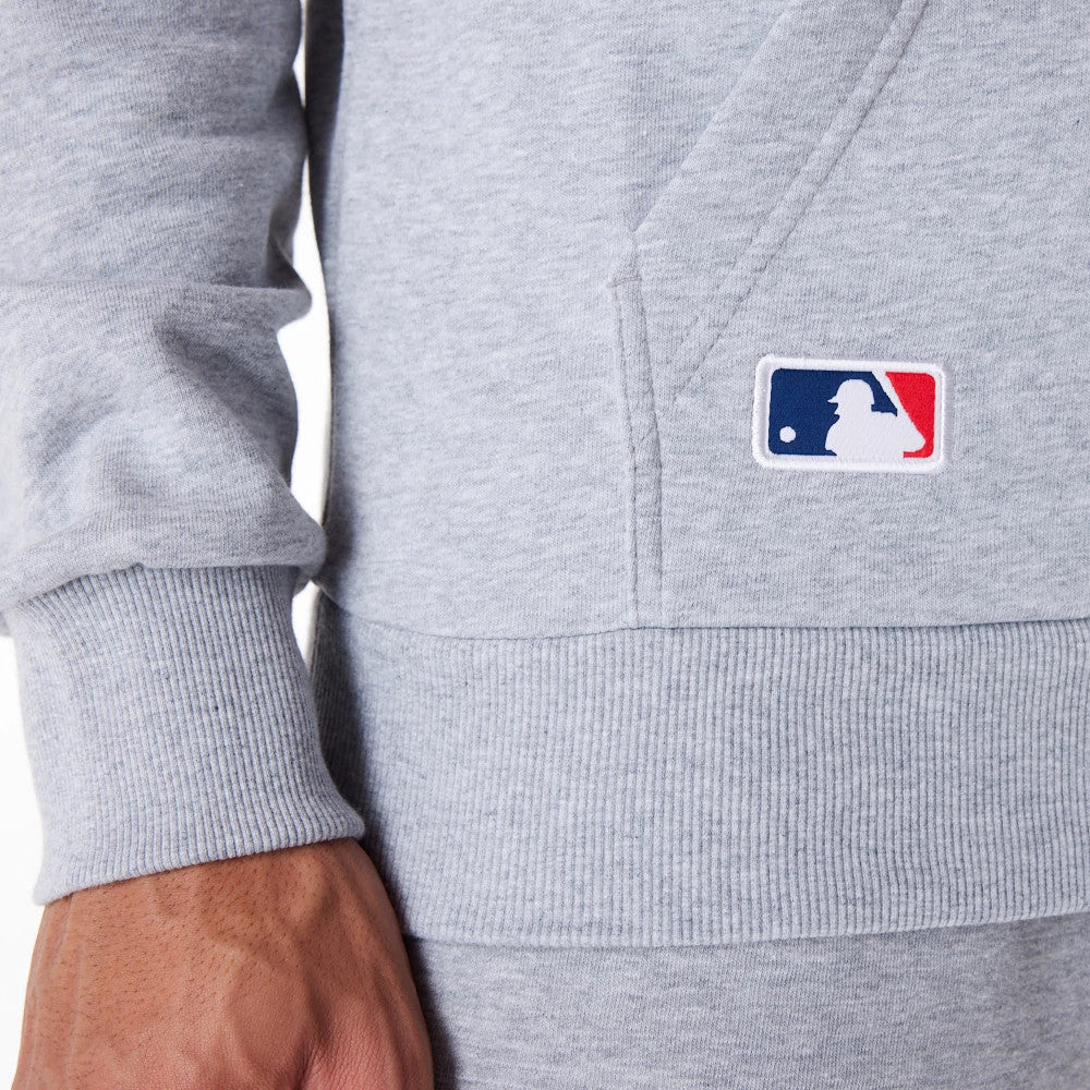 LA Dodgers MLB Regular Grey Pullover Hoodie, close-up view showing the ribbed cuff on the sleeve and the front pouch pocket, with a raised MLB logo patch on the lower edge of the hoodie near the pocket seam.