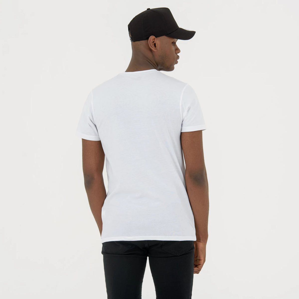 Brooklyn Nets NBA Regular White T-Shirt, on-model rear view showing the plain white back of the tee with short sleeves, paired with a black cap on the model's head, no visible logo on the shirt.