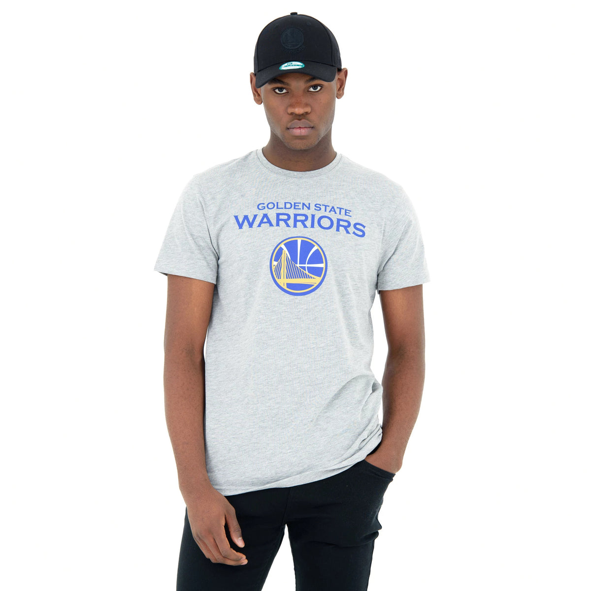 Golden State Warriors NBA Regular Grey T-Shirt, on-model view showing the grey T-shirt with blue and yellow team logo and text on the chest, paired with black trousers and a black cap featuring a raised New Era logo.