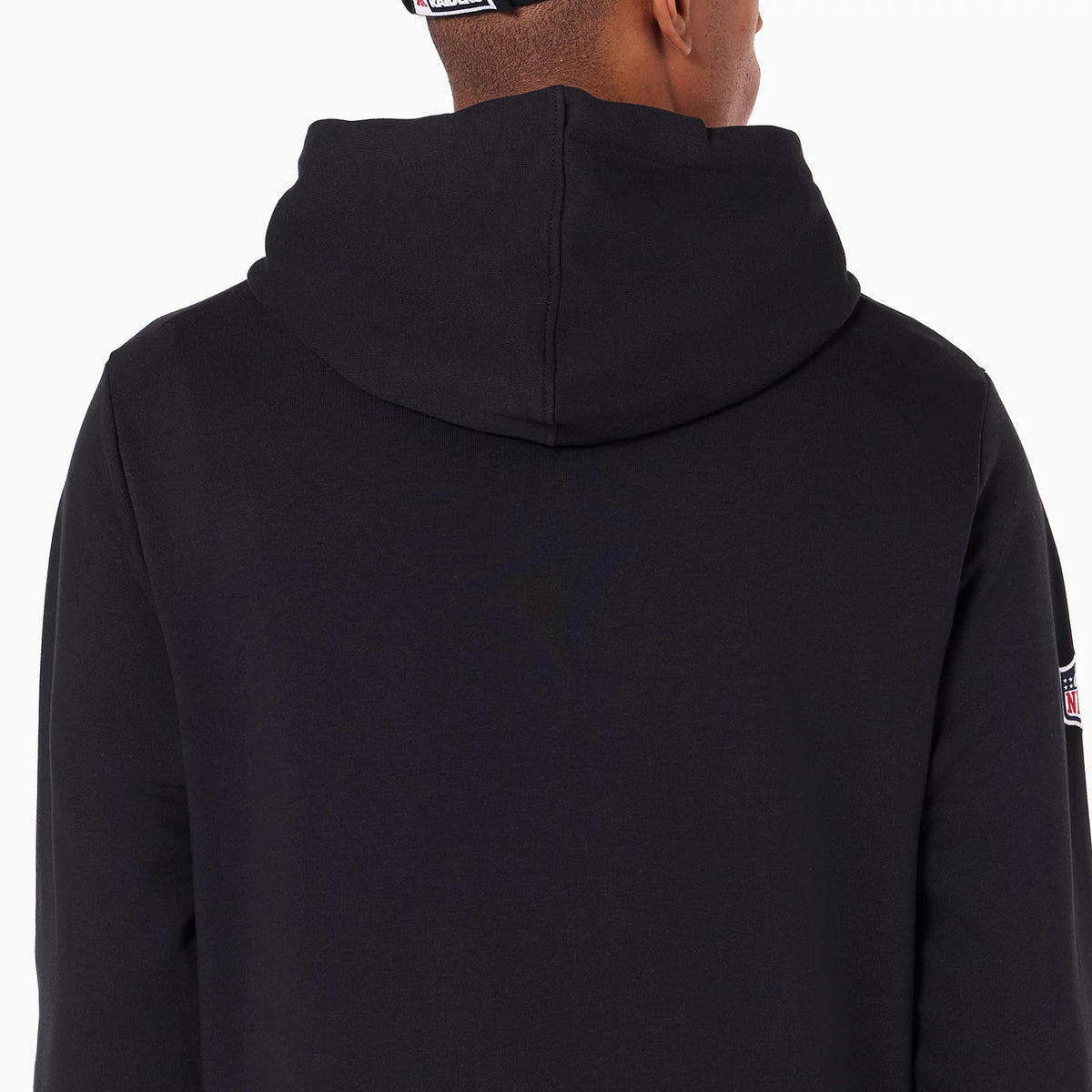 New Era Las Vegas Raiders NFL Black Pullover Hoodie, rear view showing the plain black back with a relaxed hood draped over the shoulders and an embroidered NFL logo patch on the right arm near the cuff.