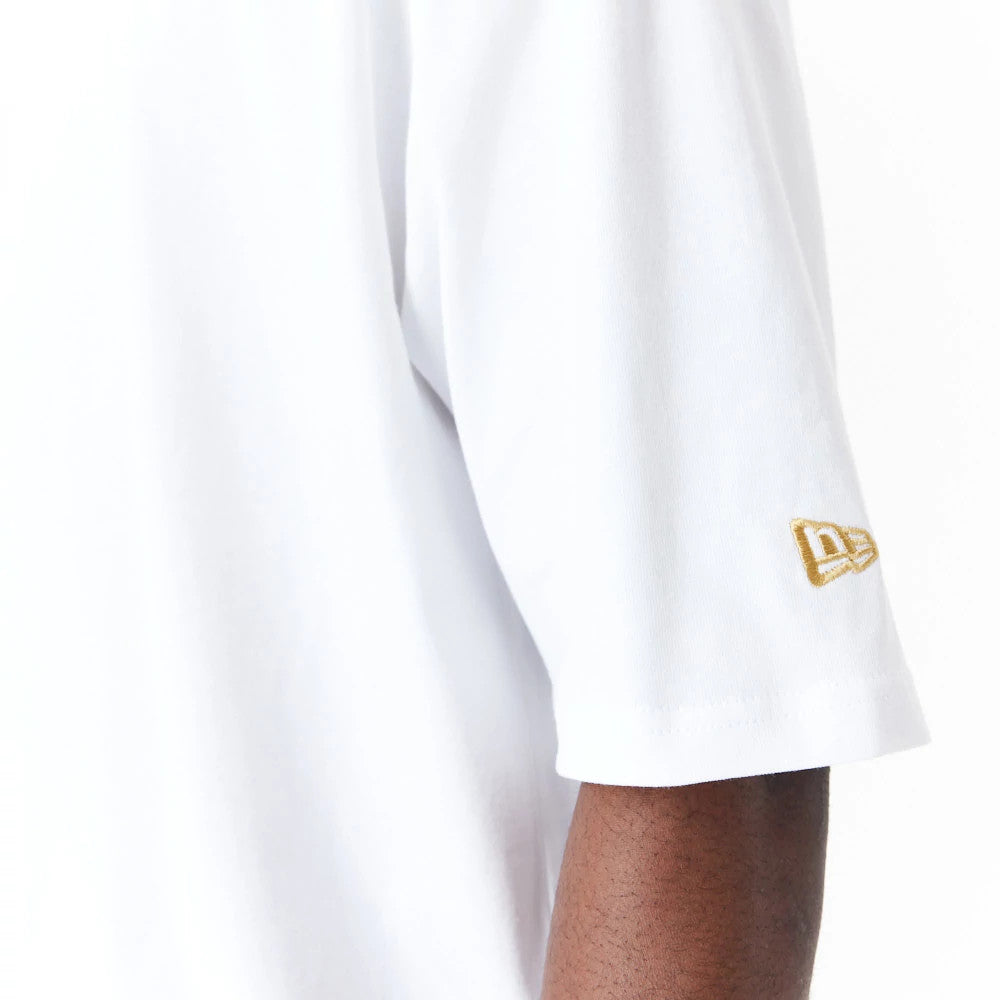 New Era Sticker White Oversized T-Shirt, side view showing the sleeve of the white shirt with a raised gold New Era logo embroidered near the hem, the fabric draping slightly on the arm.