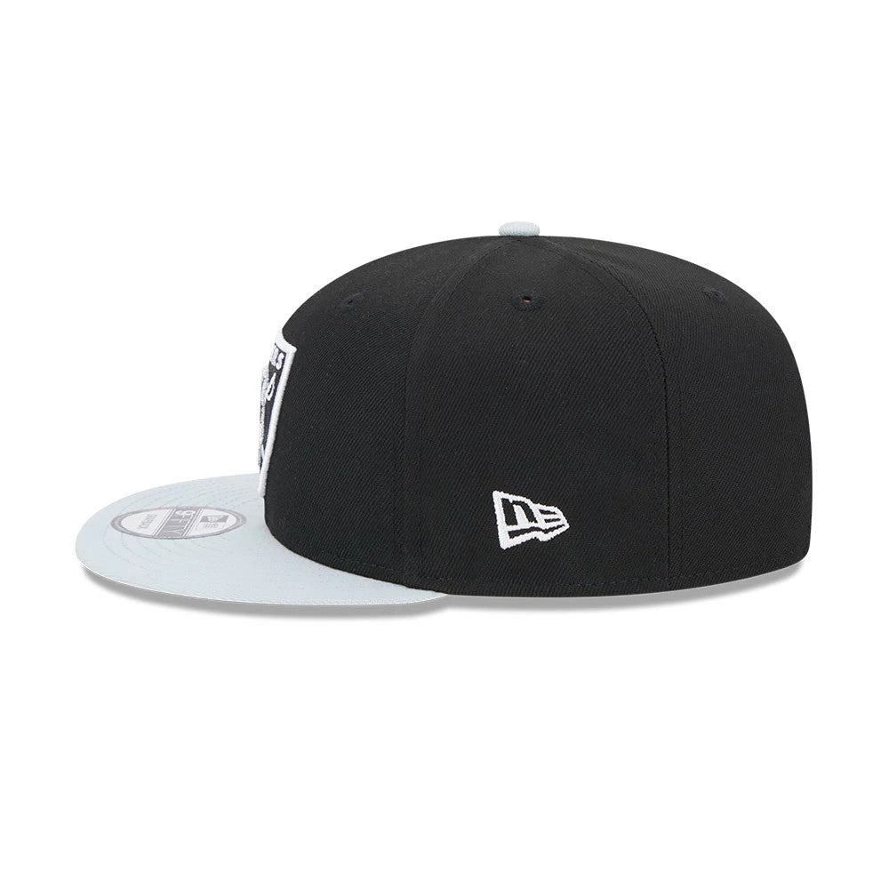 Las Vegas Raiders NFL Evergreen Black New Era 9FIFTY Snapback Adjustable Cap, side view showing white New Era flag logo on the left panel of the black structured crown, with a light grey flat visor and 9FIFTY size sticker.