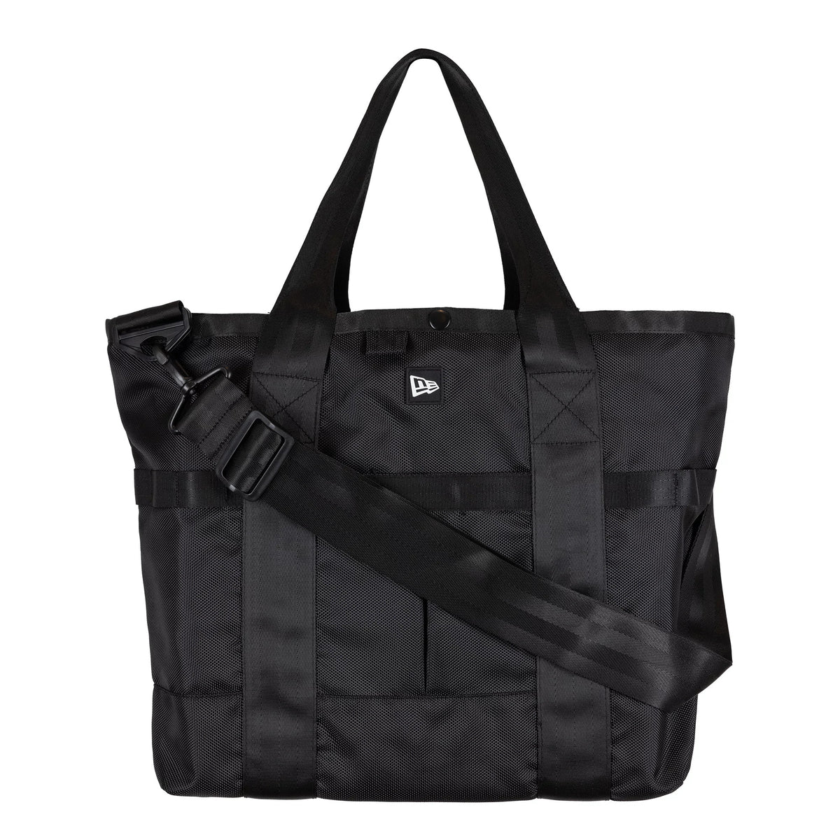 New Era Black Utility Tote Bag, front view showing the black tote with dual carry handles, a wide adjustable shoulder strap crossing the bag, and a raised New Era logo centred on the upper front panel.