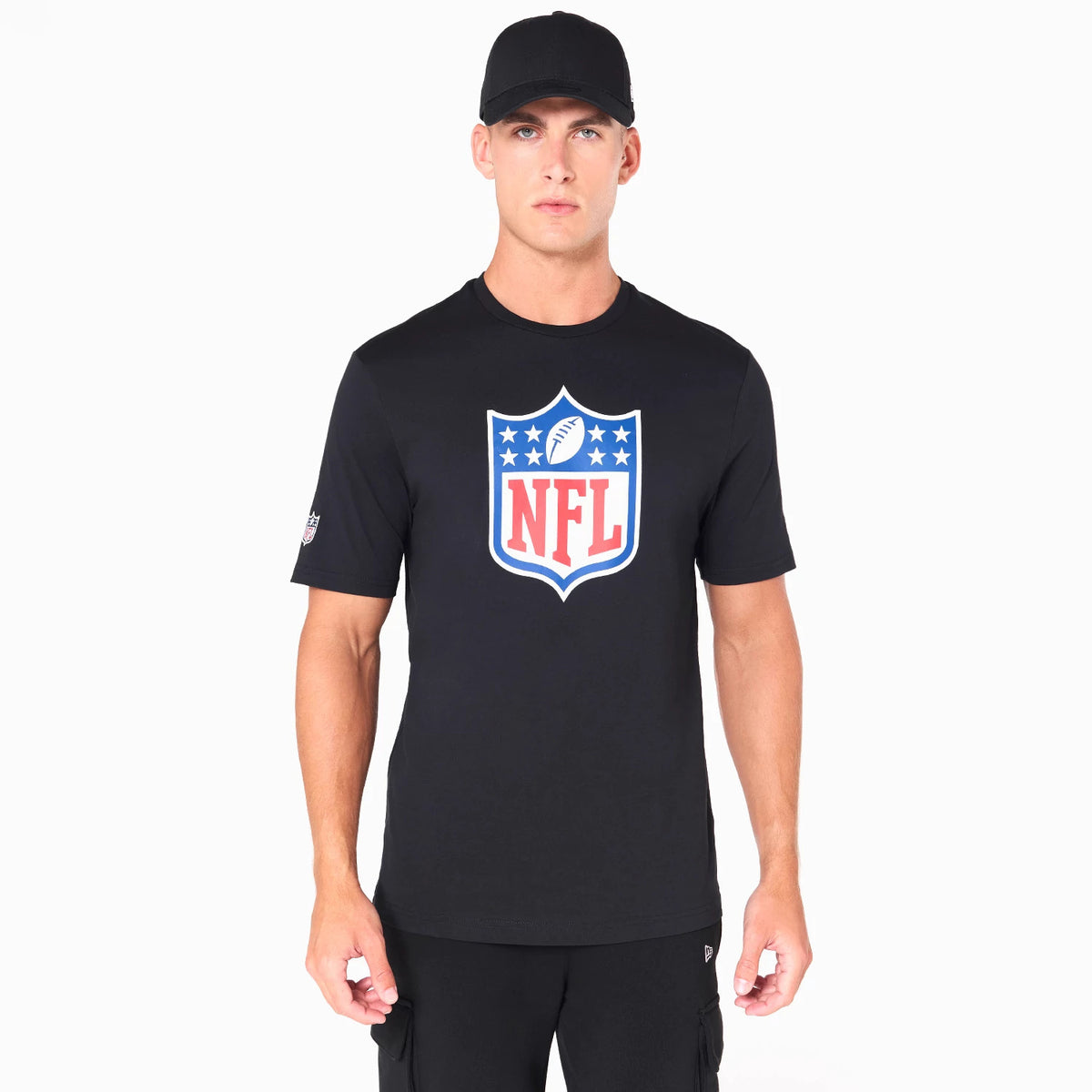 New Era NFL Shield Logo NFL Black T-Shirt, on-model view showing a large shield design in red, white, and blue at the chest, a debossed New Era logo on the sleeve, and a black cap worn by the model.