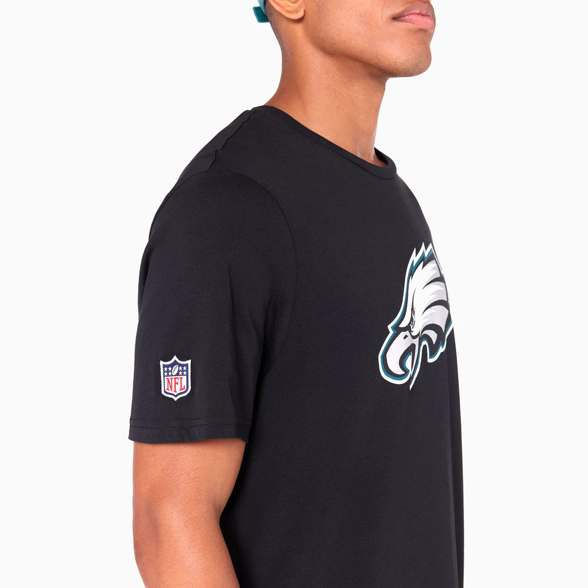 New Era Philadelphia Eagles NFL Black T-Shirt, side view showing a black shirt with a large printed Eagles logo on the chest and an embroidered NFL shield logo on the sleeve, worn by a model in profile.