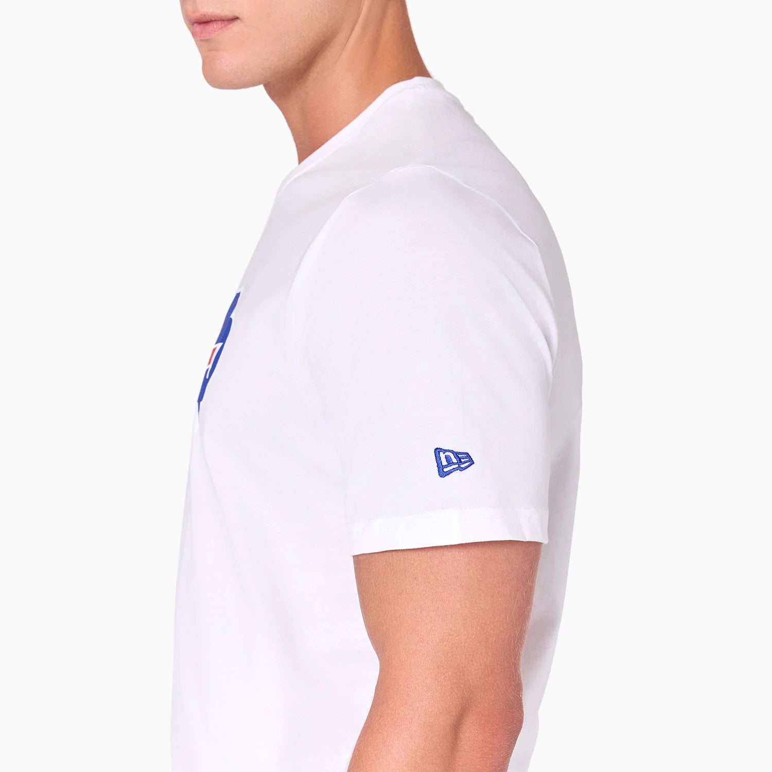 New Era Buffalo Bills NFL White T-Shirt, side view showing the plain white fabric with a small blue embroidered New Era logo on the sleeve and part of the large blue and red graphic on the front partly seen at the torso.