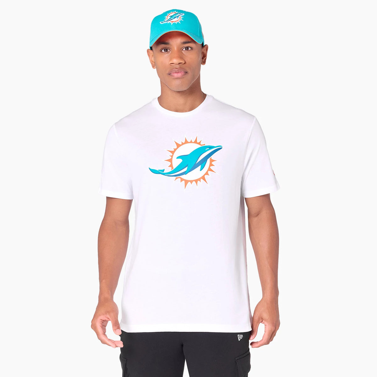 New Era Miami Dolphins NFL White T-Shirt, on-model view showing a man wearing a white t-shirt with the Miami Dolphins logo centred on the chest, paired with a teal cap featuring a raised logo on the front.