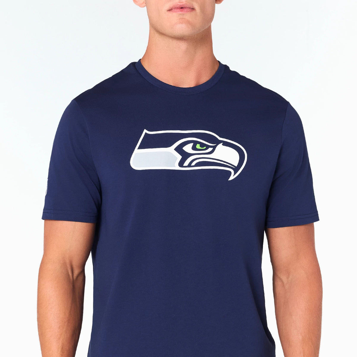 New Era Seattle Seahawks NFL Navy T-Shirt, front view showing the large printed team logo with a white and grey seahawk head centred on the chest against a dark navy fabric backdrop with short sleeves.