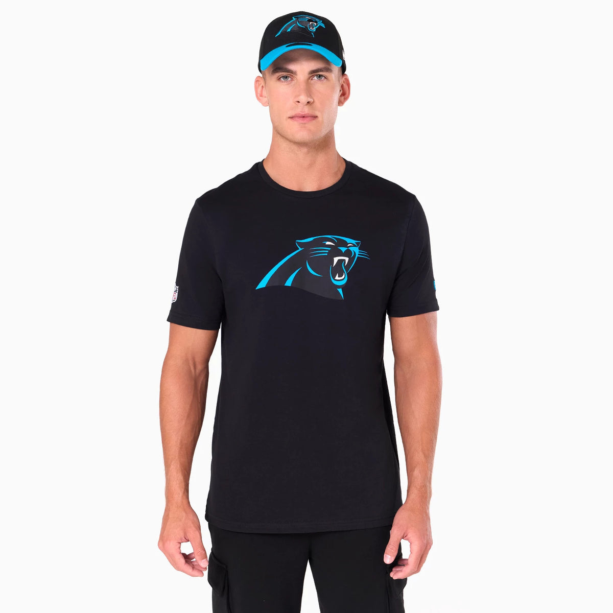 New Era Carolina Panthers NFL Black T-Shirt, on-model view showing the black T-shirt with a large blue Carolina Panthers logo centred on the chest and a small logo on the left sleeve, worn with a matching cap featuring an embossed logo on the front.