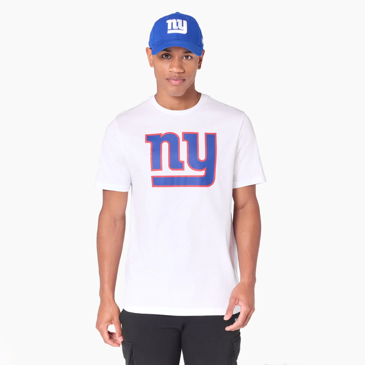 New Era New York Giants NFL White T-Shirt, on-model view showing the large blue and red ny graphic centred on the white shirt, paired with a blue cap featuring a raised white ny logo on the front.