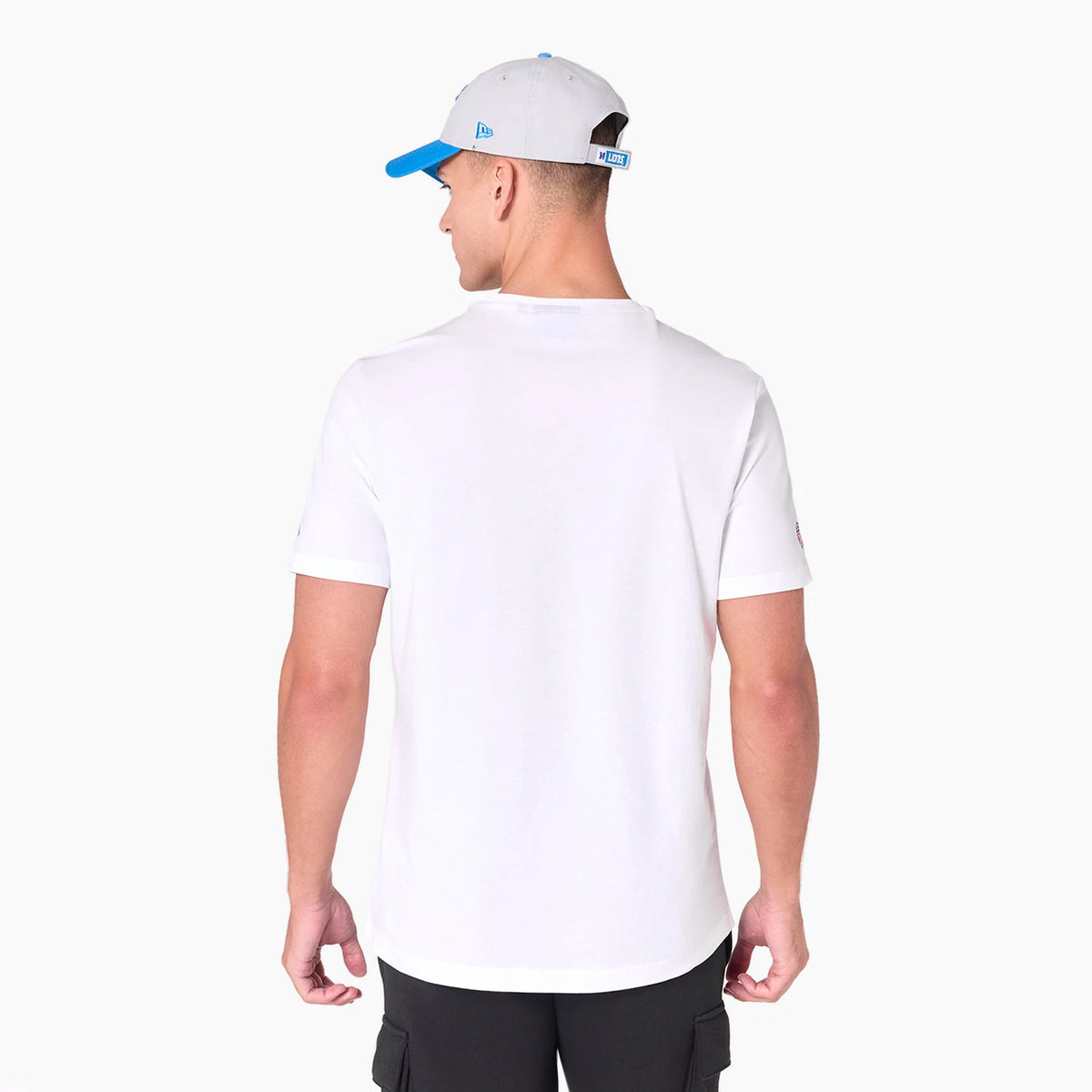 New Era Detroit Lions NFL White T-Shirt, on-model rear view showing a plain white back extended to short sleeves, accompanied by a grey cap with a blue visor and debossed logo on the side, worn by the model.