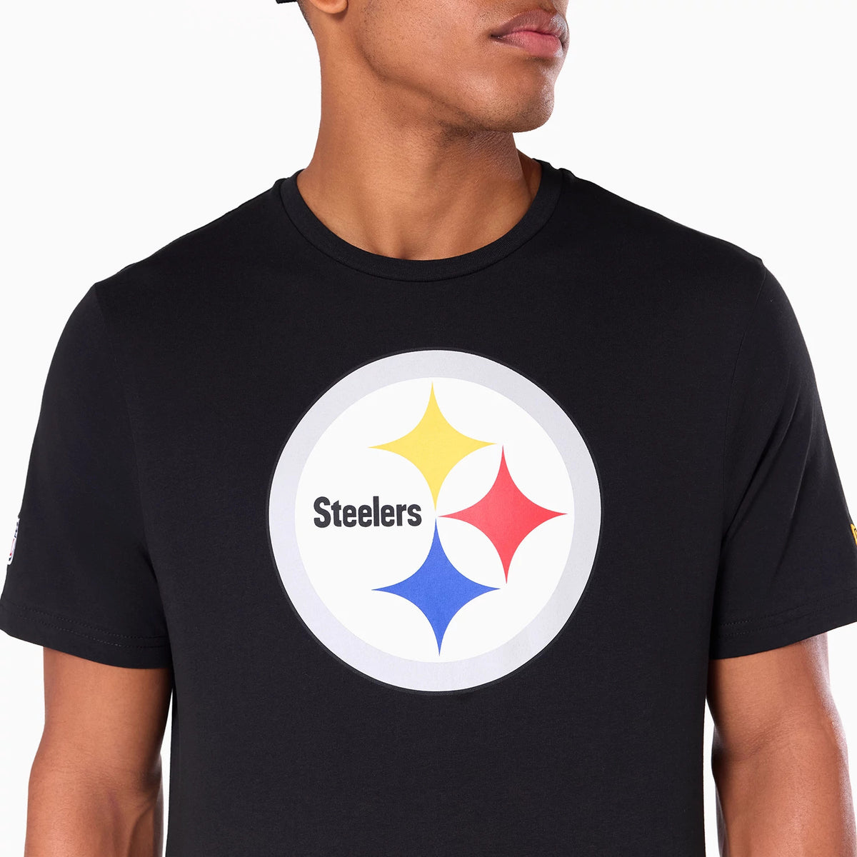 New Era Pittsburgh Steelers NFL Black T-Shirt, front view showing a large circular Steelers logo in the centre featuring yellow, red, and blue stars on a black background worn by a model.