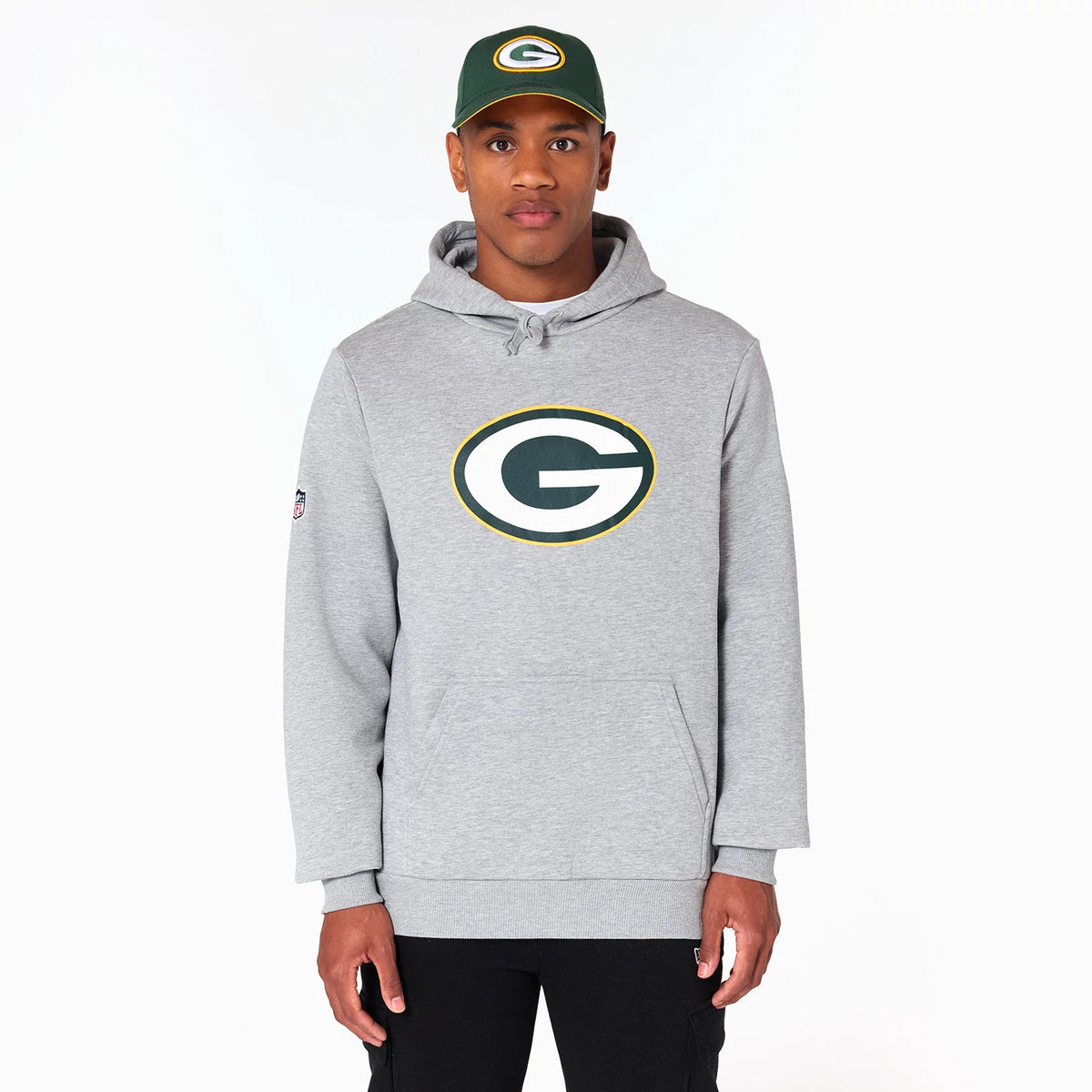 New Era Green Bay Packers NFL Grey Pullover Hoodie, on-model view showing a large printed Packers logo on the chest and an embroidered patch on the left sleeve, with the hood resting at the back and adjustable drawstrings at the neckline.