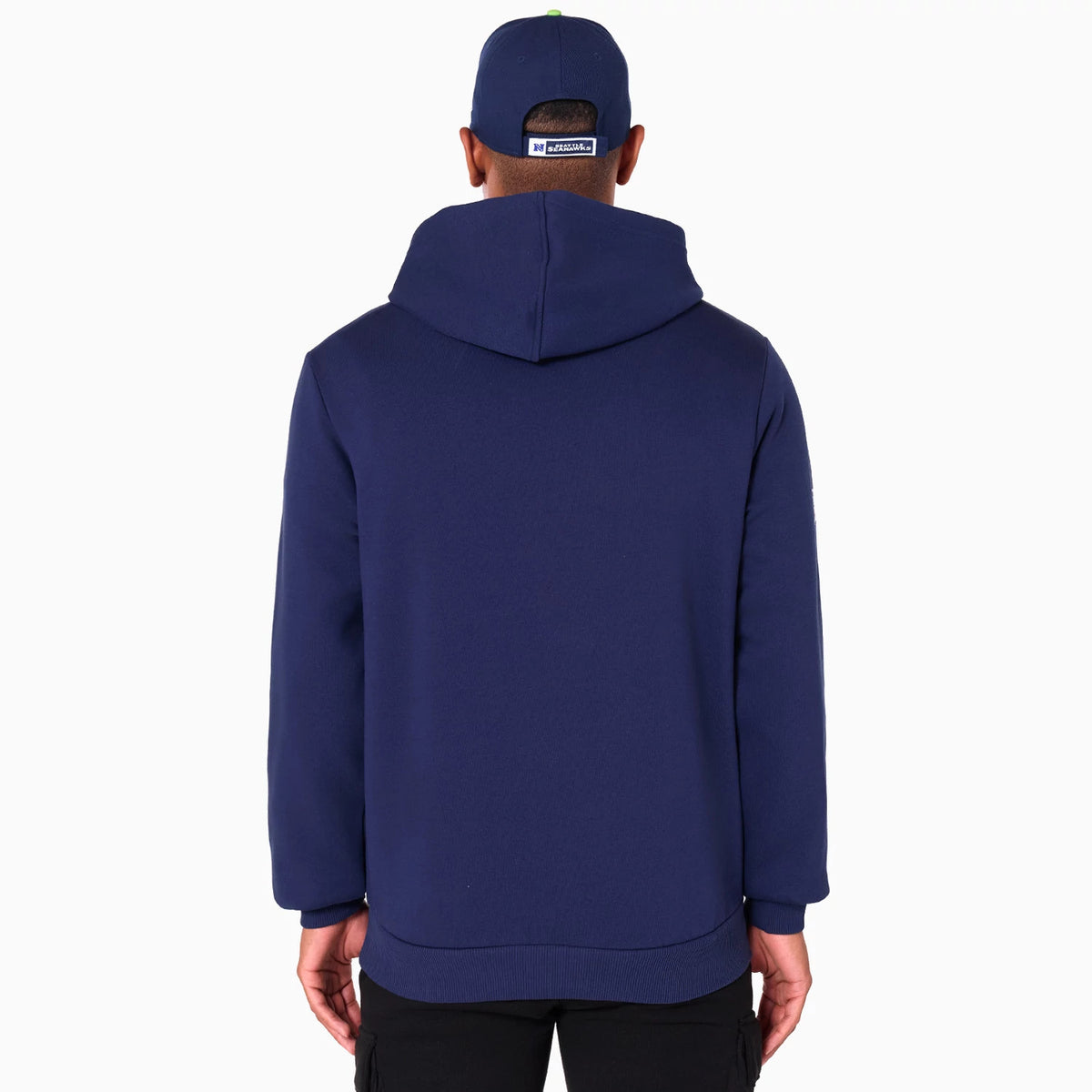 New Era Seattle Seahawks NFL Navy Pullover Hoodie, rear view showing a plain navy back with an attached hood, worn by a person also wearing a navy cap with a white raised New Era logo on the back.