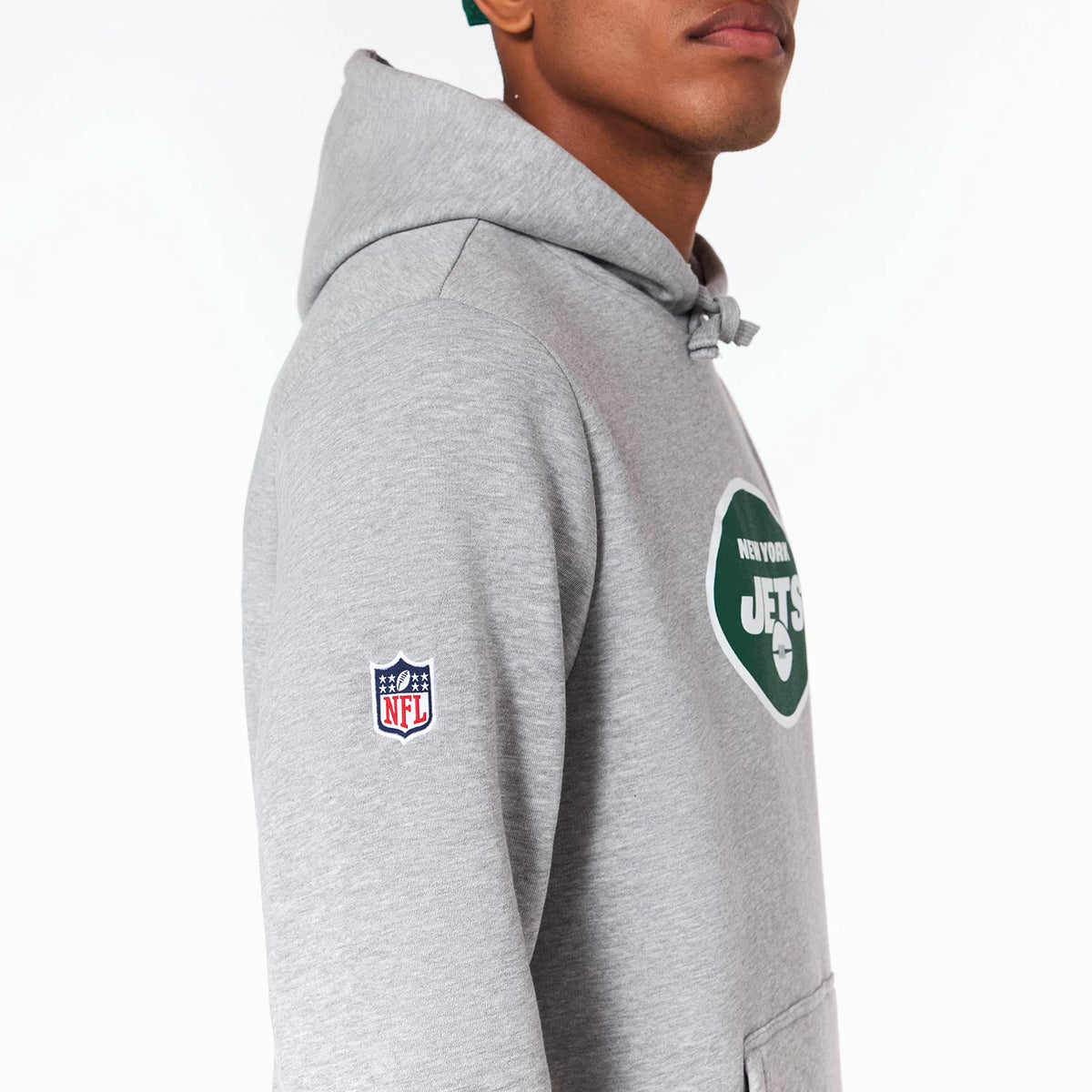 New Era New York Jets NFL Grey Pullover Hoodie, side view showing the grey fabric with the green and white New York Jets logo printed on the chest and the embroidered NFL logo in red, white, and blue on the left sleeve.
