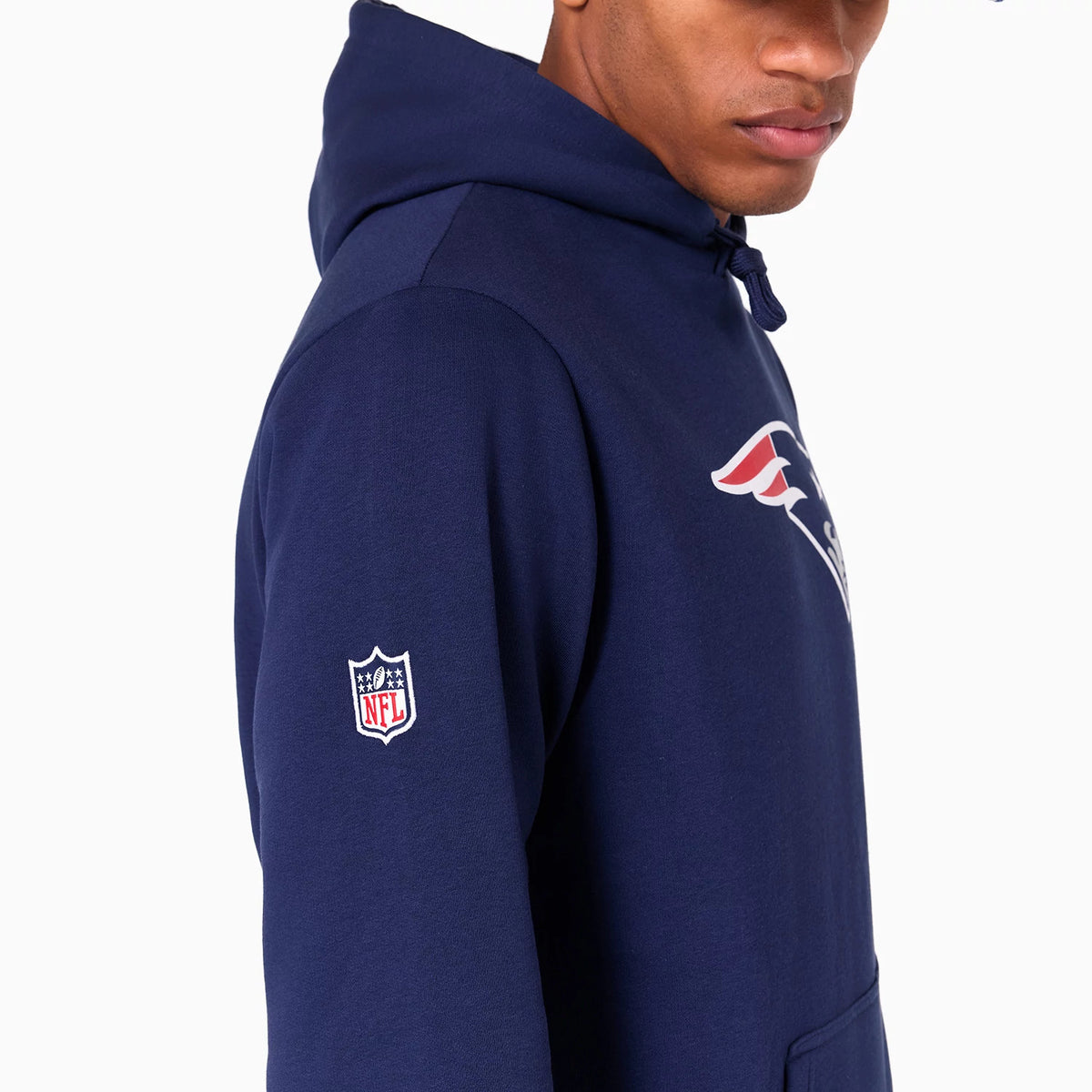 New Era New England Patriots NFL Navy Pullover Hoodie, side view showing the navy fabric with a raised New England Patriots logo on the chest, a white embroidered NFL logo on the sleeve and a hood with navy drawstrings.