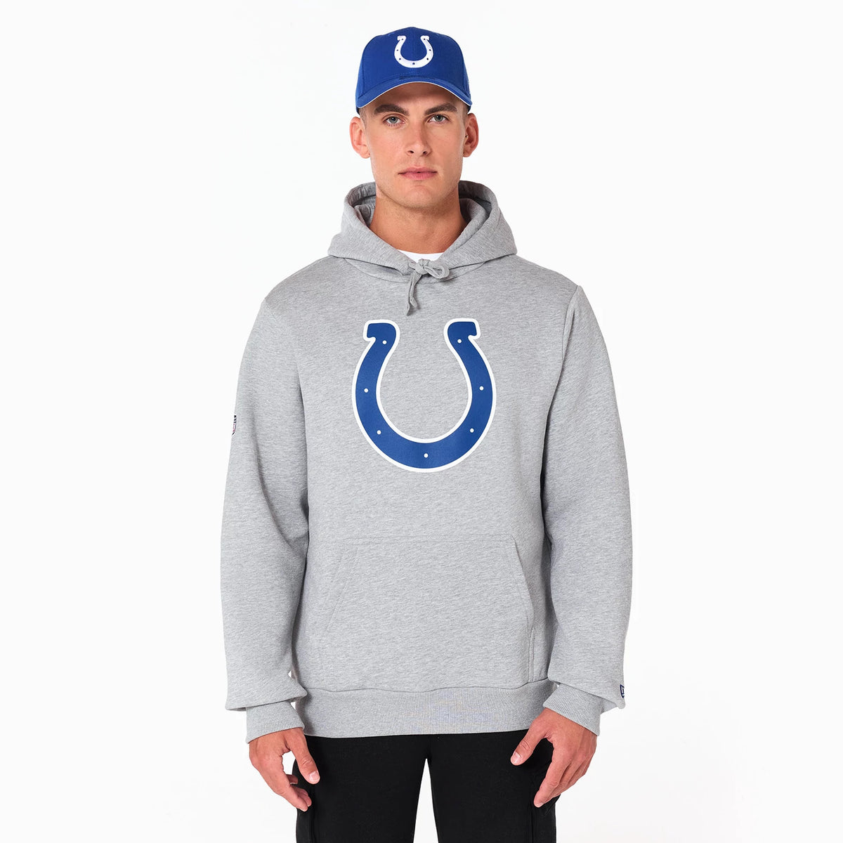 New Era Indianapolis Colts NFL Grey Pullover Hoodie, front view featuring a large blue horseshoe logo centred on the chest, drawstring hood, and ribbed cuffs, worn by a model in a blue cap with a raised Colts logo.