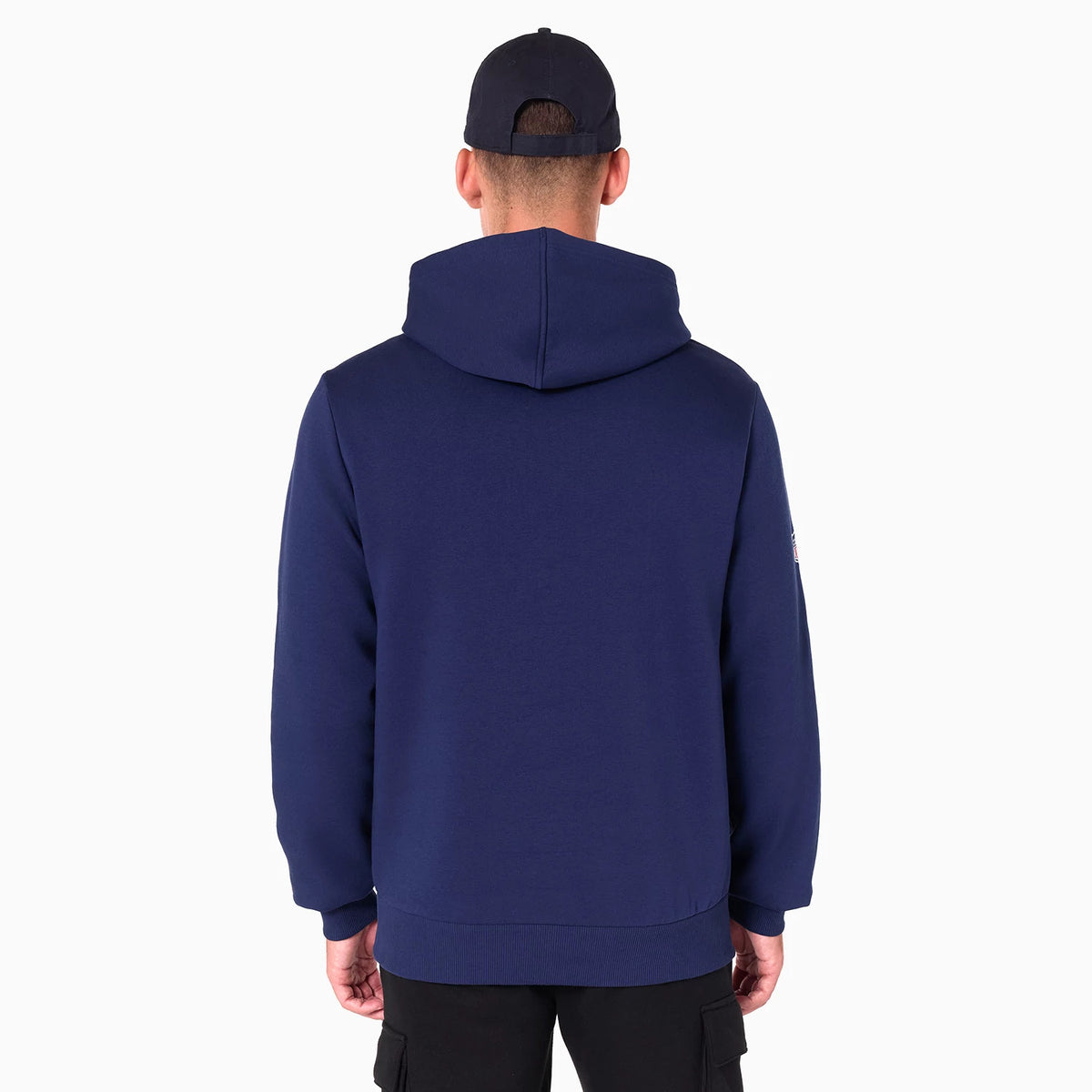 New Era Tennessee Titans NFL Navy Pullover Hoodie, rear view showing the dark navy fabric with a spacious hood and long sleeves, worn by a model in black trousers and a black cap, featuring a small logo on the left sleeve.
