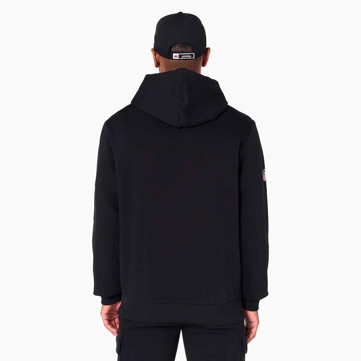 New Era Jacksonville Jaguars NFL Black Pullover Hoodie, rear view showing a plain black back with a large hood, a raised logo on the right sleeve and a man wearing a black cap with a debossed logo on the back.