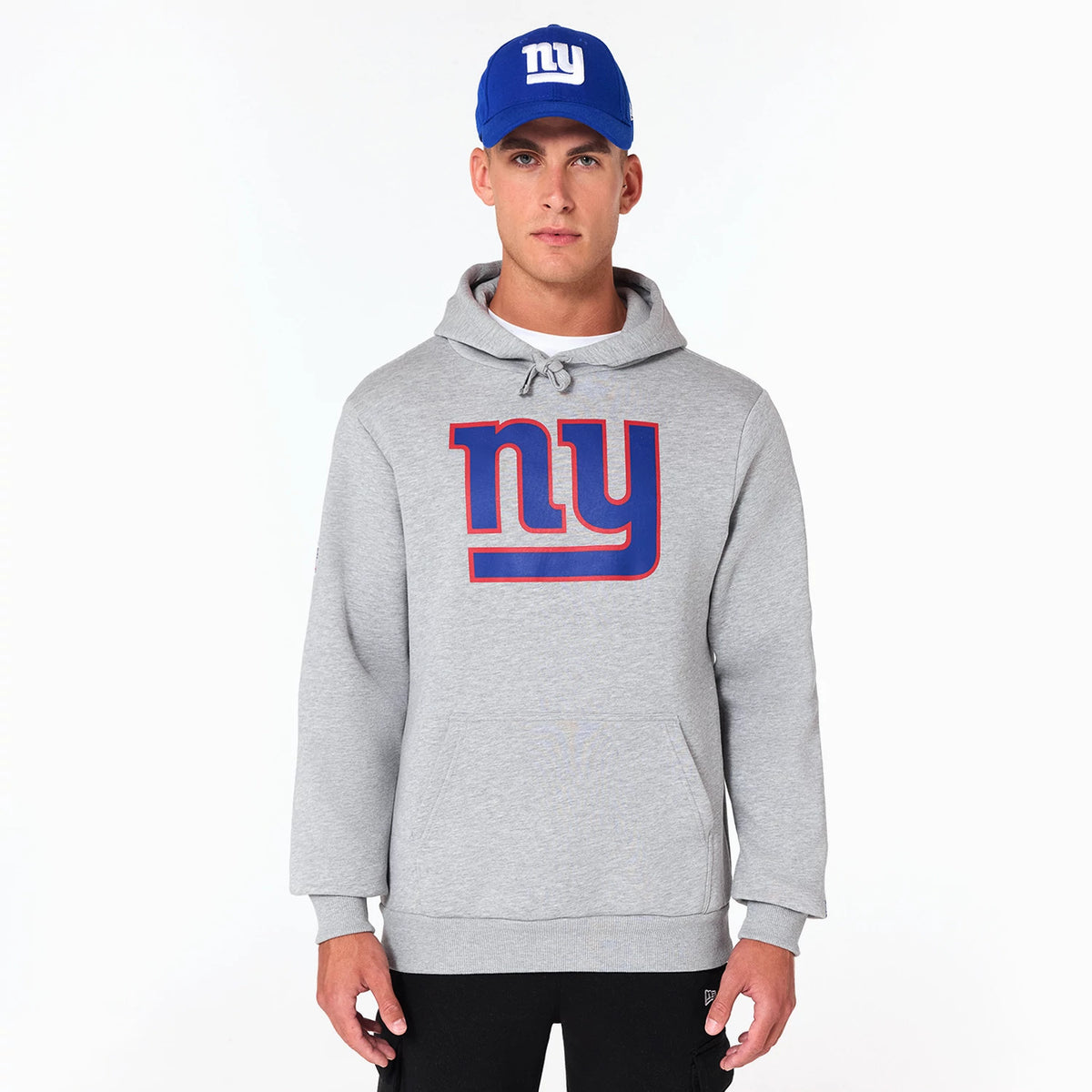 New Era New York Giants NFL Grey Pullover Hoodie, front view showing the large blue and red outlined ny logo on the chest, drawstrings at the hood and ribbed cuffs at the wrists, worn by a model with a blue cap featuring a raised ny logo.
