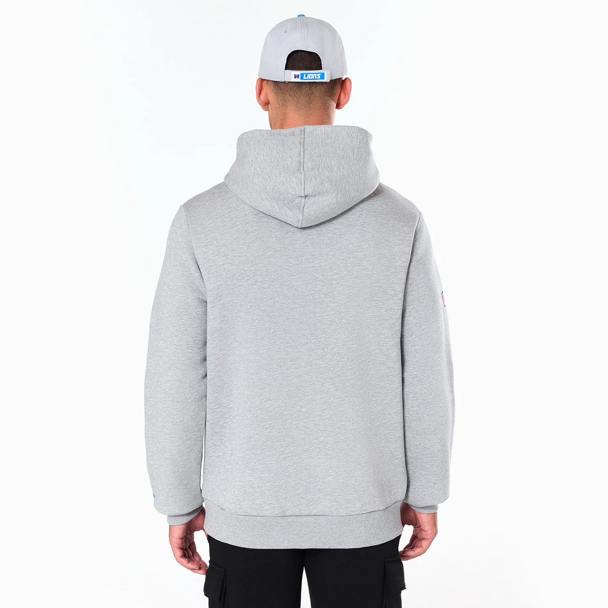 New Era Detroit Lions NFL Grey Pullover Hoodie, rear view showing the plain grey back and large hood, worn by a person also wearing a grey cap with a raised Lions logo centred on the back strap above the neck.