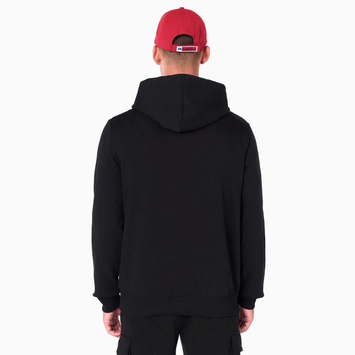 New Era Arizona Cardinals NFL Black Pullover Hoodie, rear view showing a plain black hood and back, worn by a person in black trousers and a red cap with a raised logo on the back.