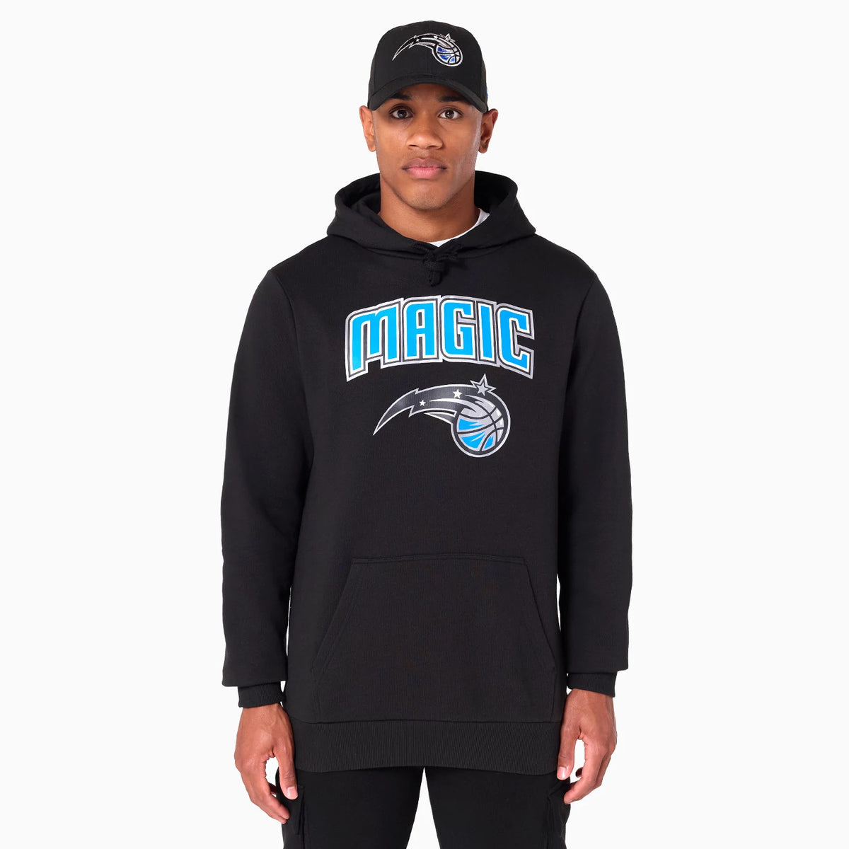 New Era Orlando Magic NBA Black Pullover Hoodie, on-model view showing the front graphic in blue and white with the Magic logo, paired with a black cap featuring an embroidered team logo on the front.