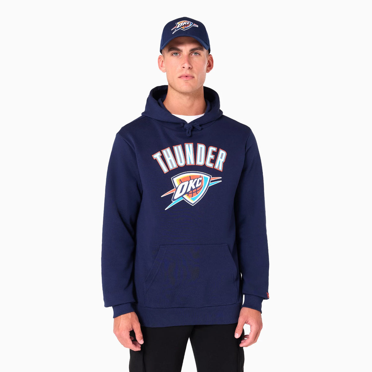 New Era Oklahoma City Thunder NBA Navy Pullover Hoodie, on-model view showing the large printed Thunder logo across the chest, with a hood on top and paired with a matching navy cap featuring a raised logo above the visor.