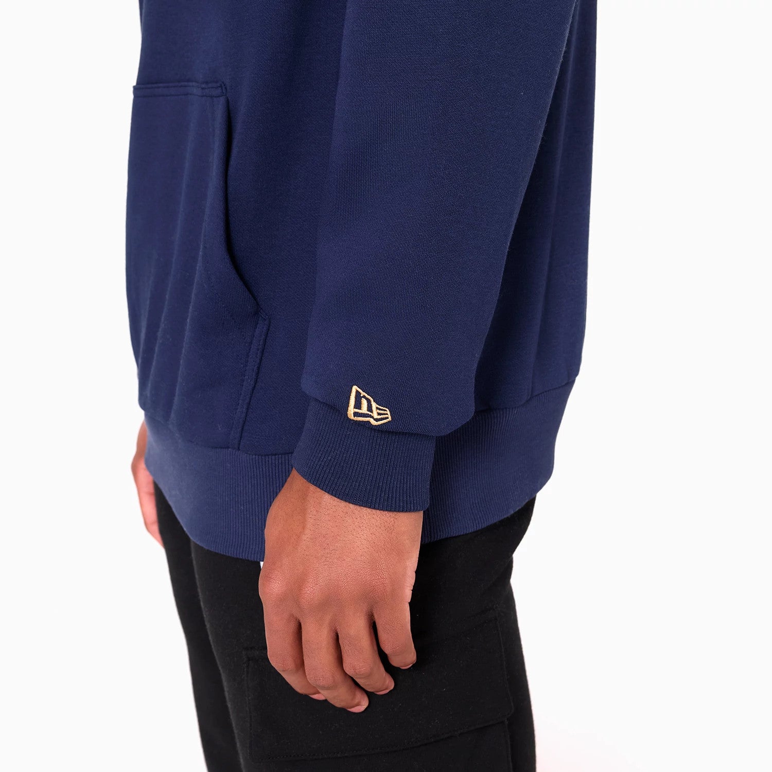 New Era Cleveland Cavaliers NBA Navy Pullover Hoodie, side view showing the navy fabric with a kangaroo pocket at the front, ribbed cuffs at the wrists, and a raised New Era logo embroidered in gold on the sleeve.