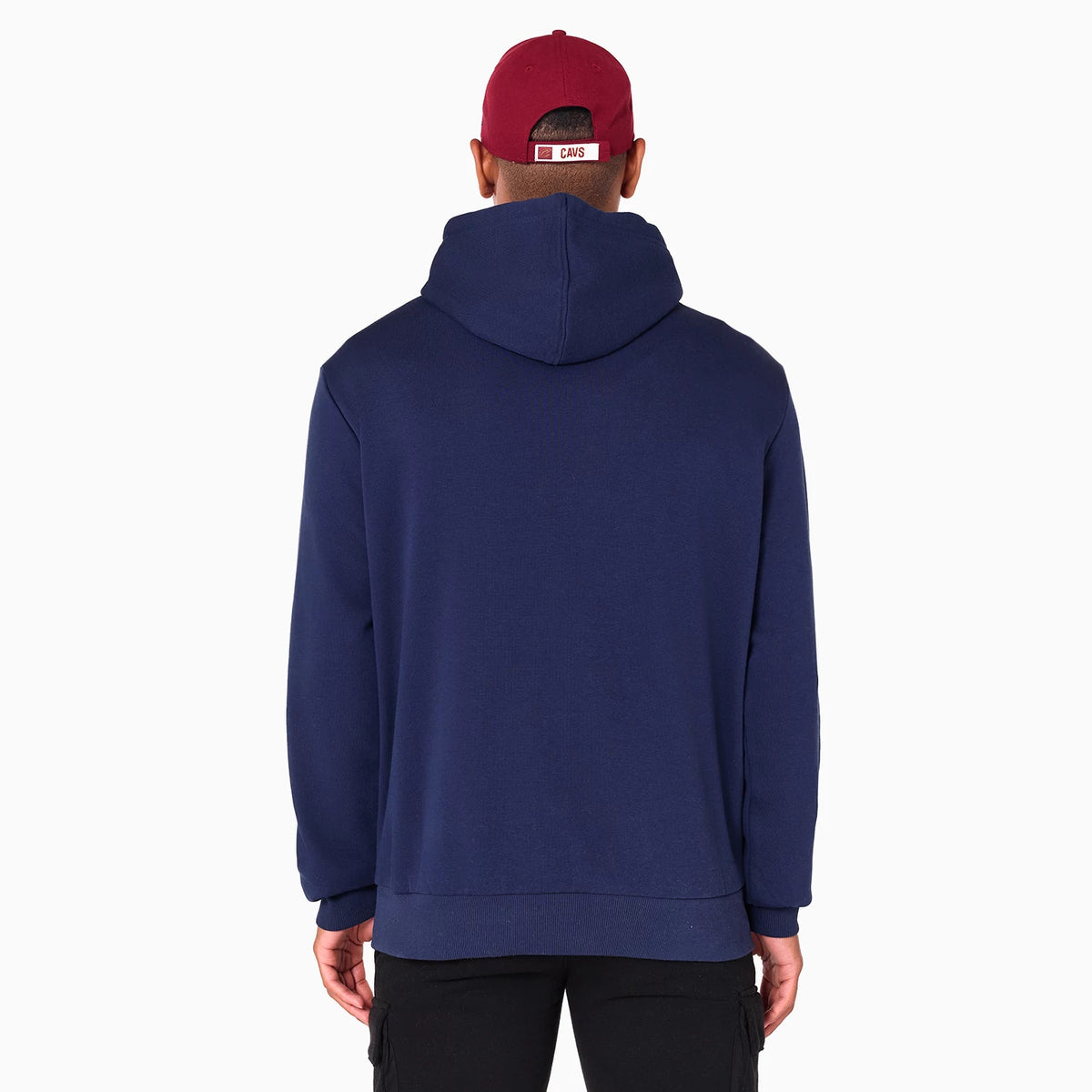 New Era Cleveland Cavaliers NBA Navy Pullover Hoodie, on-model rear view showing the relaxed fit with a navy hood laying flat, long sleeves with ribbed cuffs, and a model wearing a red cap with eyelets and a raised logo on the back strap.