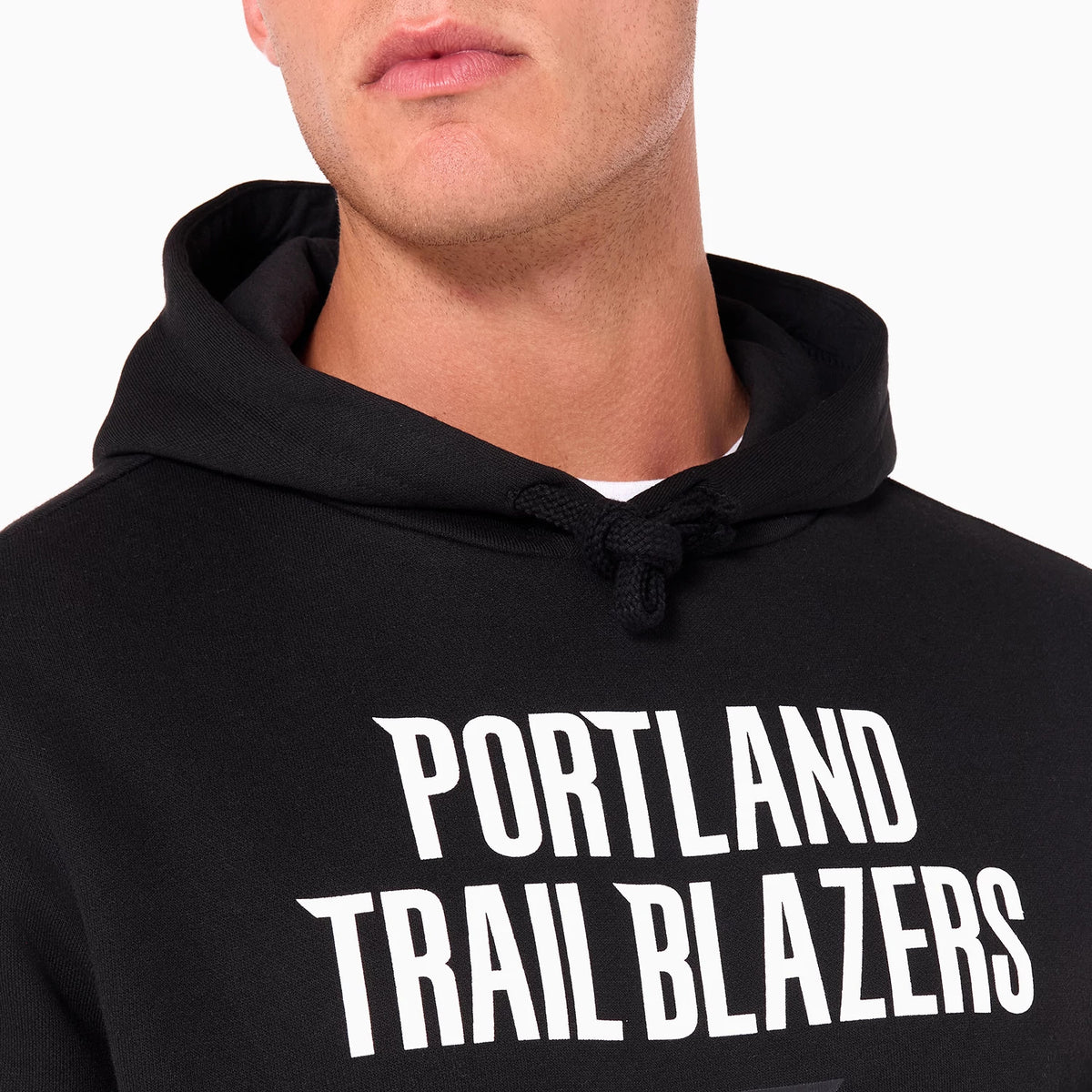 New Era Portland Trail Blazers NBA Black Pullover Hoodie, on-model view showing the upper section of the black hoodie with the white Portland Trail Blazers text across the chest and the hood's drawstrings tied at the front.