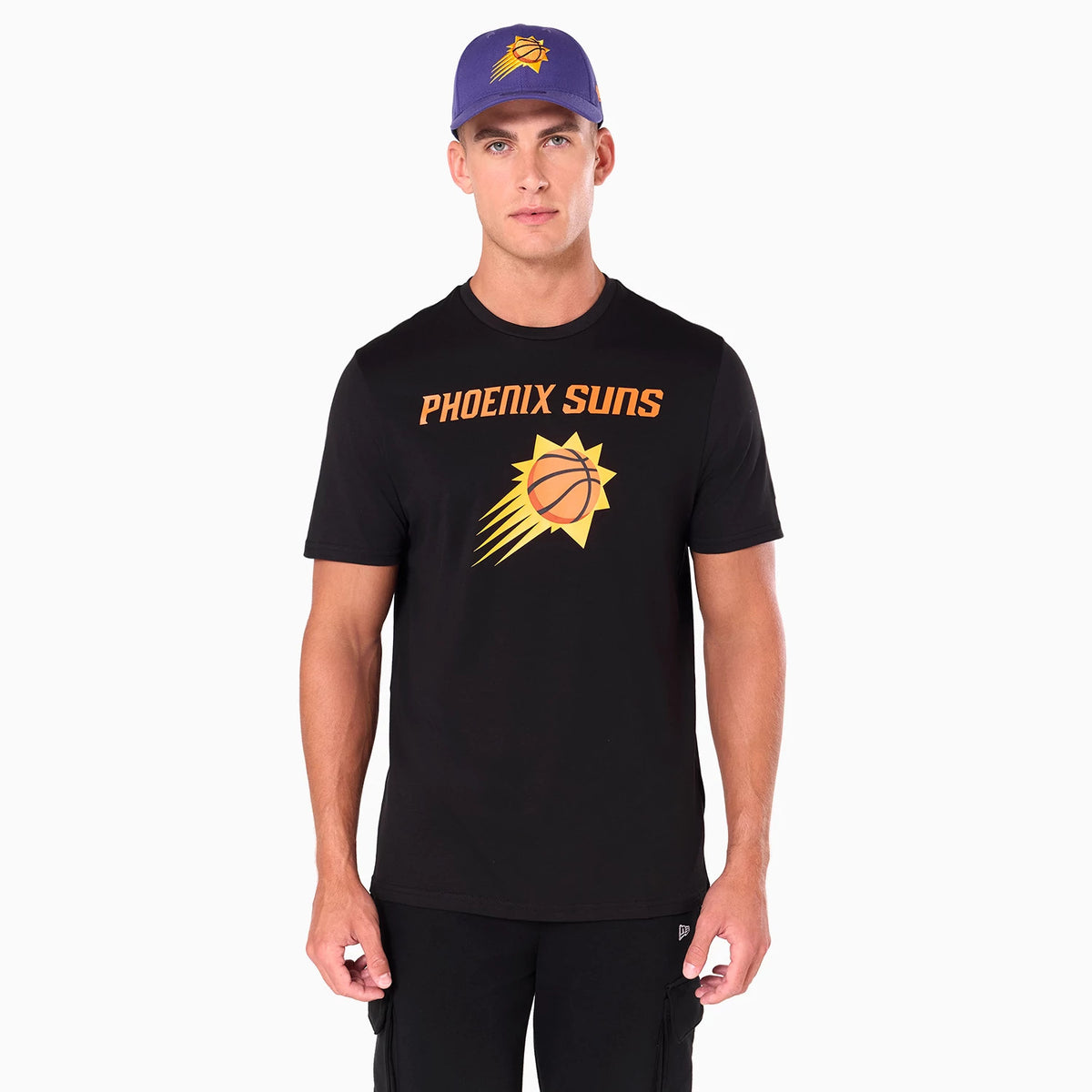 New Era Phoenix Suns NBA Black T-Shirt, on-model view showing the black short-sleeve shirt with a large orange Phoenix Suns logo on the chest, worn by a man in black shorts and a purple cap with a debossed logo.