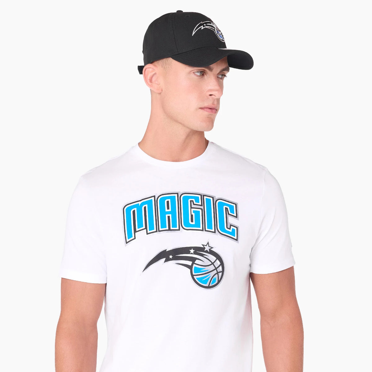 New Era Orlando Magic NBA White T-Shirt, on-model view showing a black cap with a debossed Orlando Magic logo in white on the front, person wearing the cap paired with a white T-shirt featuring the large MAGIC text and team logo on the chest.