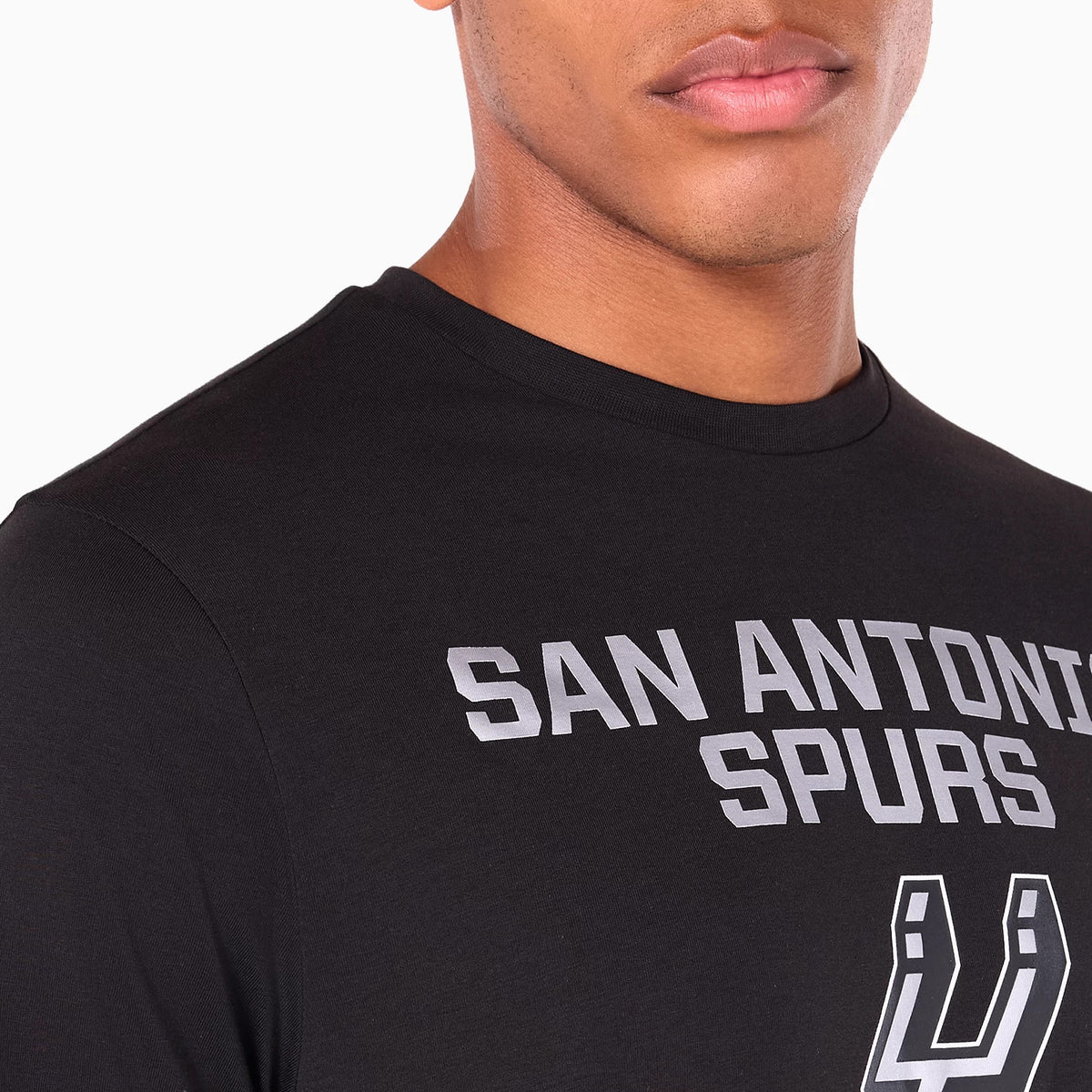 New Era San Antonio Spurs NBA Black T-Shirt, on-model view showing the front with a raised silver San Antonio Spurs wordmark across the chest and a raised silver logo below, against a black fabric.