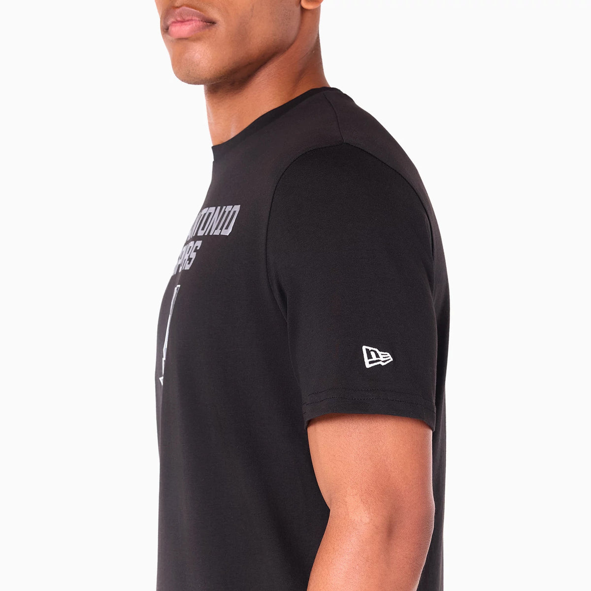 New Era San Antonio Spurs NBA Black T-Shirt, side view showing a prominent debossed New Era logo on the sleeve, the shirt's black fabric with white text across the upper chest, and the short sleeve design on the model's arm.