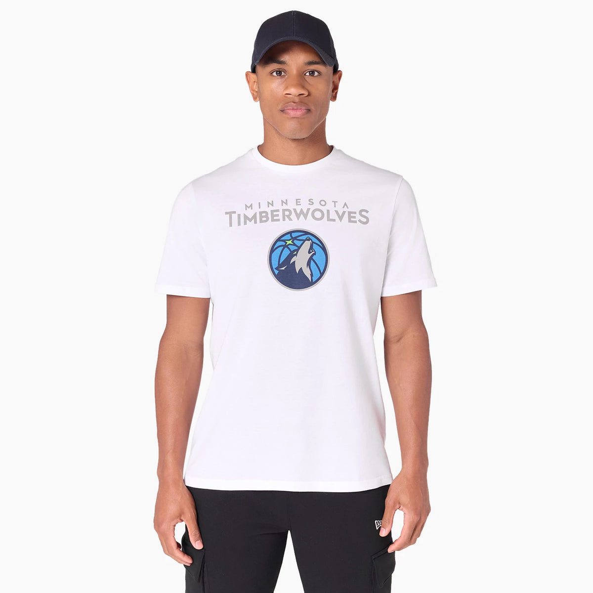 New Era Minnesota Timberwolves NBA White T-Shirt, on-model view showing the front design with the Timberwolves logo and text centred on the chest, worn with a black cap and black trousers.