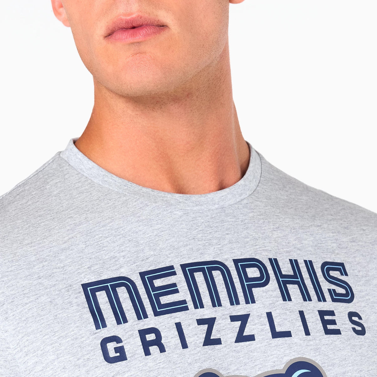 New Era Memphis Grizzlies NBA Grey T-Shirt, front view showing the close-up of the grey fabric with bold navy lettering spelling Memphis Grizzlies across the chest, partially visible graphic detail beneath the text.