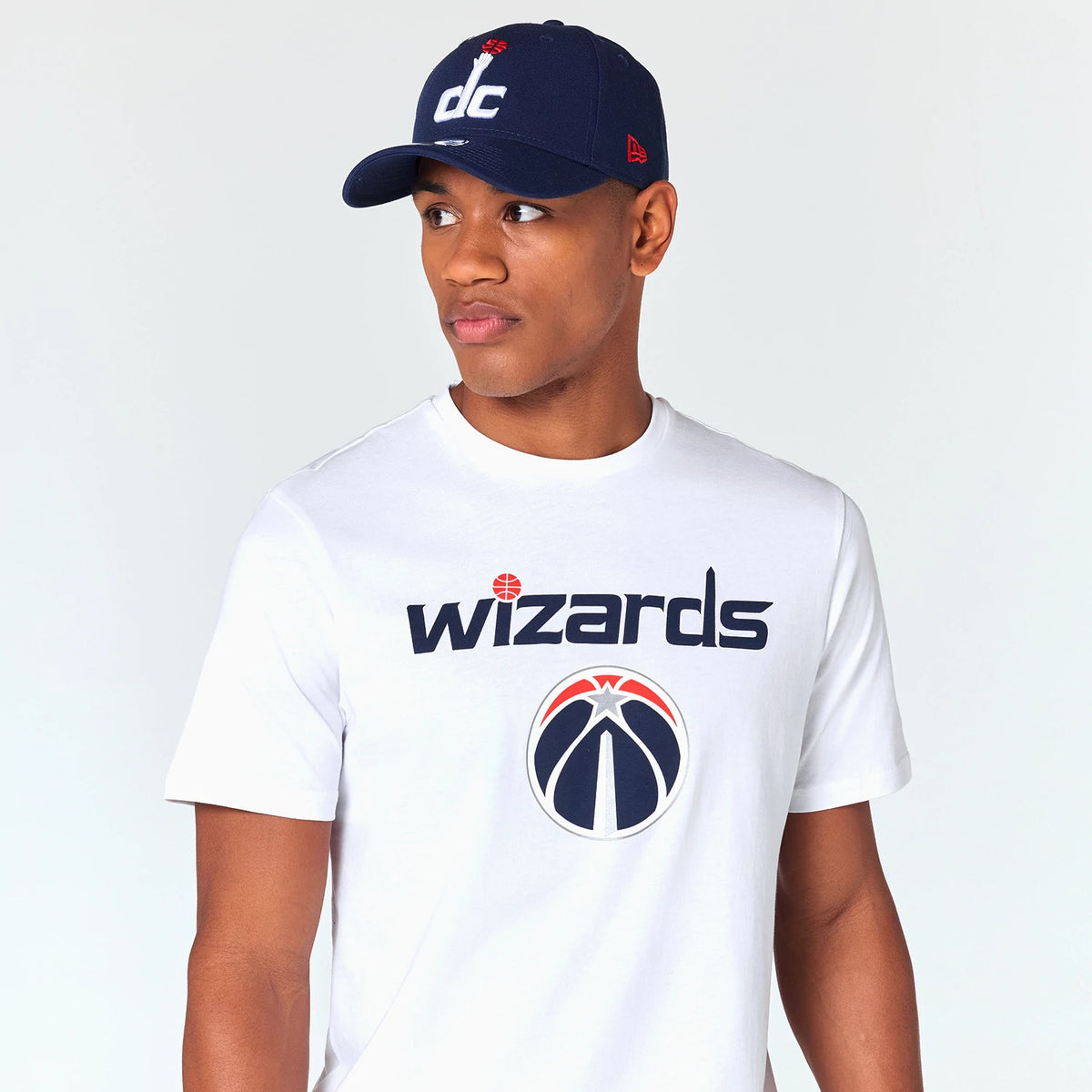 New Era Washington Wizards NBA White T-Shirt, on-model view featuring the team logo and name in navy on the chest, styled with a navy cap with a white raised dc logo and a red New Era logo on the side.