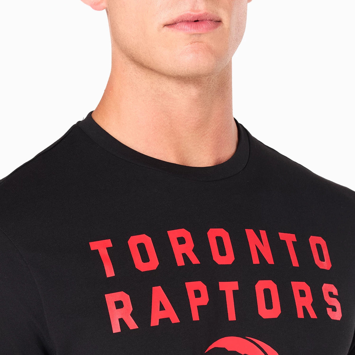 New Era Toronto Raptors NBA Black T-Shirt, front view showing bold red lettering spelling Toronto Raptors across the chest of the black shirt worn by a model, featuring a round crew neck and partial logo visible below the text.