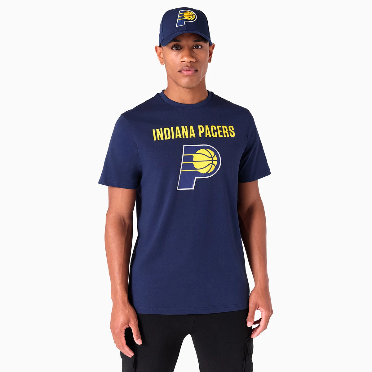 New Era Indiana Pacers NBA Graphic Navy T-Shirt, on-model showing the large yellow text and logo on the chest of the navy T-shirt, accompanied by a debossed logo on a matching navy cap worn by the model.