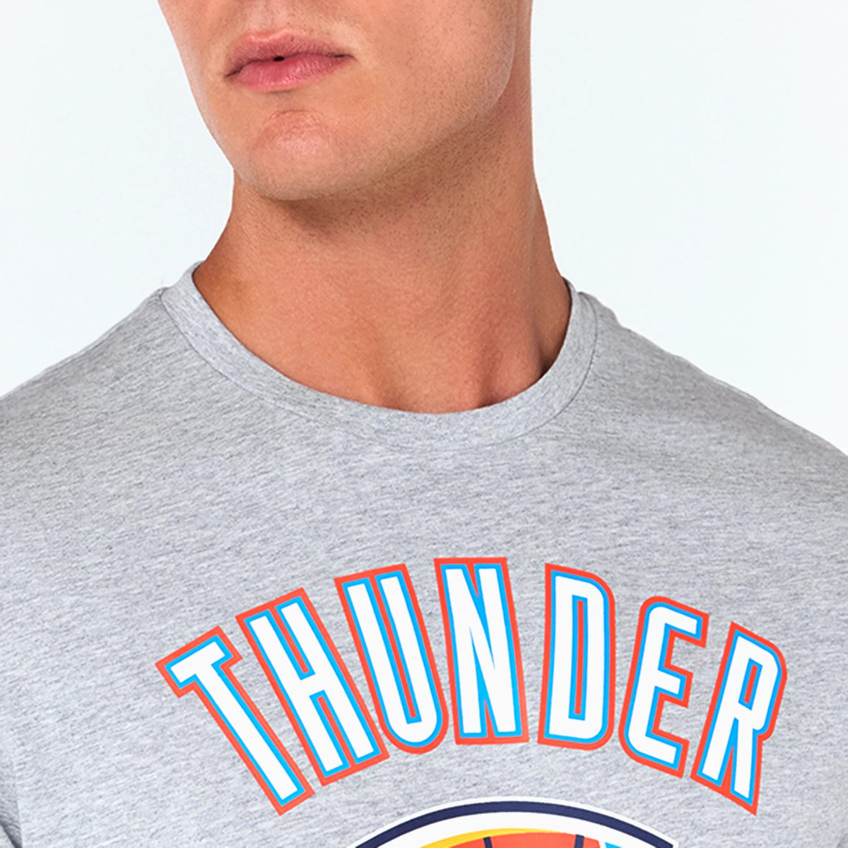 New Era Oklahoma City Thunder NBA Grey T-Shirt, front view showing the grey fabric with bold Thunder lettering in blue and orange across the chest above part of the team’s logo, rounded neckline visible.