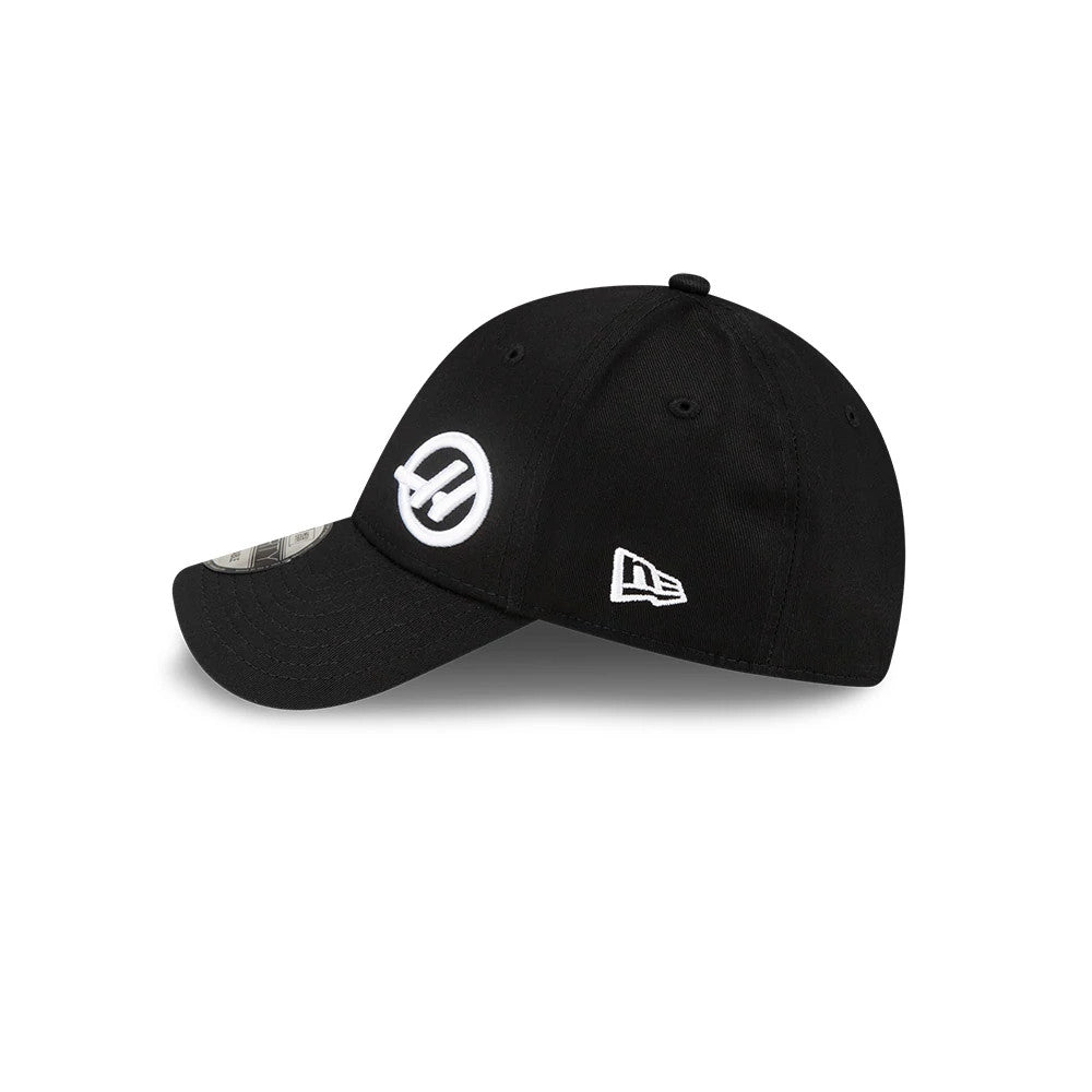 TGR Haas F1 Team Flawless Black New Era 9FORTY Adjustable Cap, side view showing the white embroidered Haas logo on the front panel, the New Era flag logo on the left side, and the 9FORTY size sticker on the black visor.