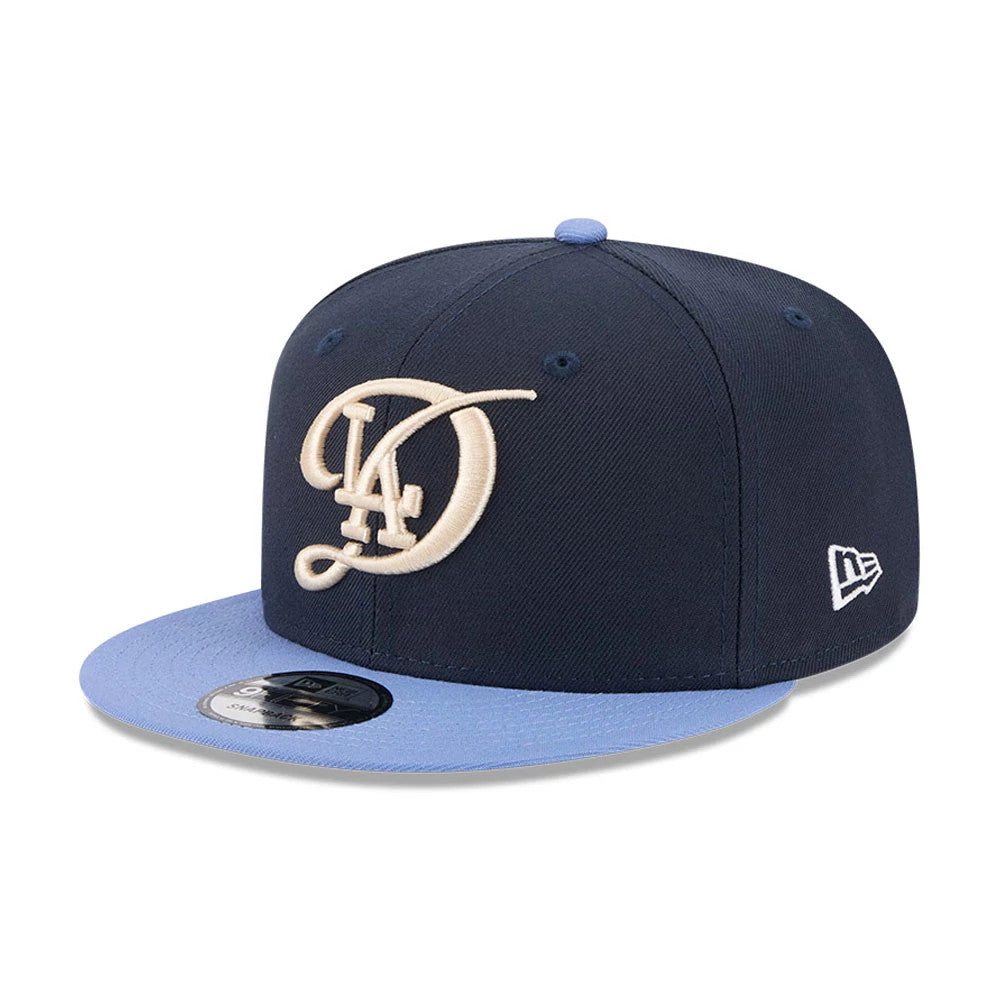 LA Dodgers MLB Evergreen Dark Blue New Era 9FIFTY Snapback Adjustable Cap, front view with a raised cream LA logo embroidered on the dark blue crown, light blue visor, and New Era flag logo on the left side.
