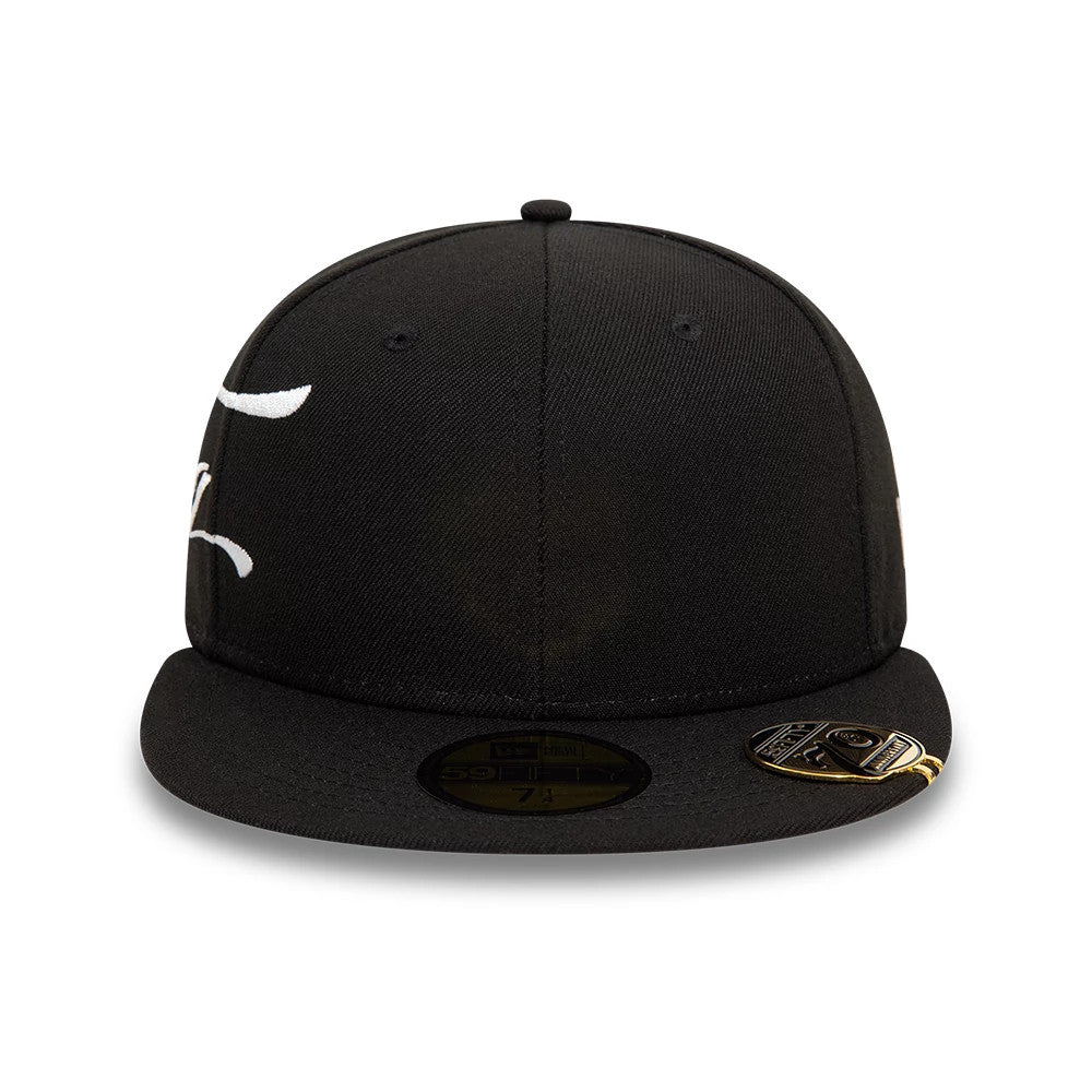 New Era Side Script Black 59FIFTY Fitted Cap, front view showing raised white embroidery on the black crown, a gold 59FIFTY size sticker centred on the black visor, and a decorative metallic pin on the left side of the visor.
