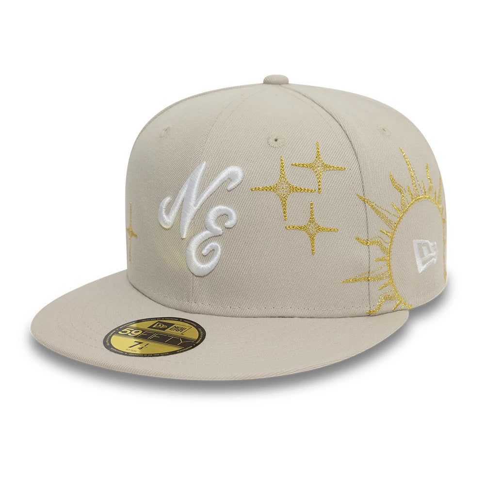 New Era Zodiac Light Beige New Era 59FIFTY Fitted Cap, front view showing raised white NE embroidery, gold embroidered zodiac symbols on the crown, gold 59FIFTY size sticker on the peak, and white New Era flag logo on the right.
