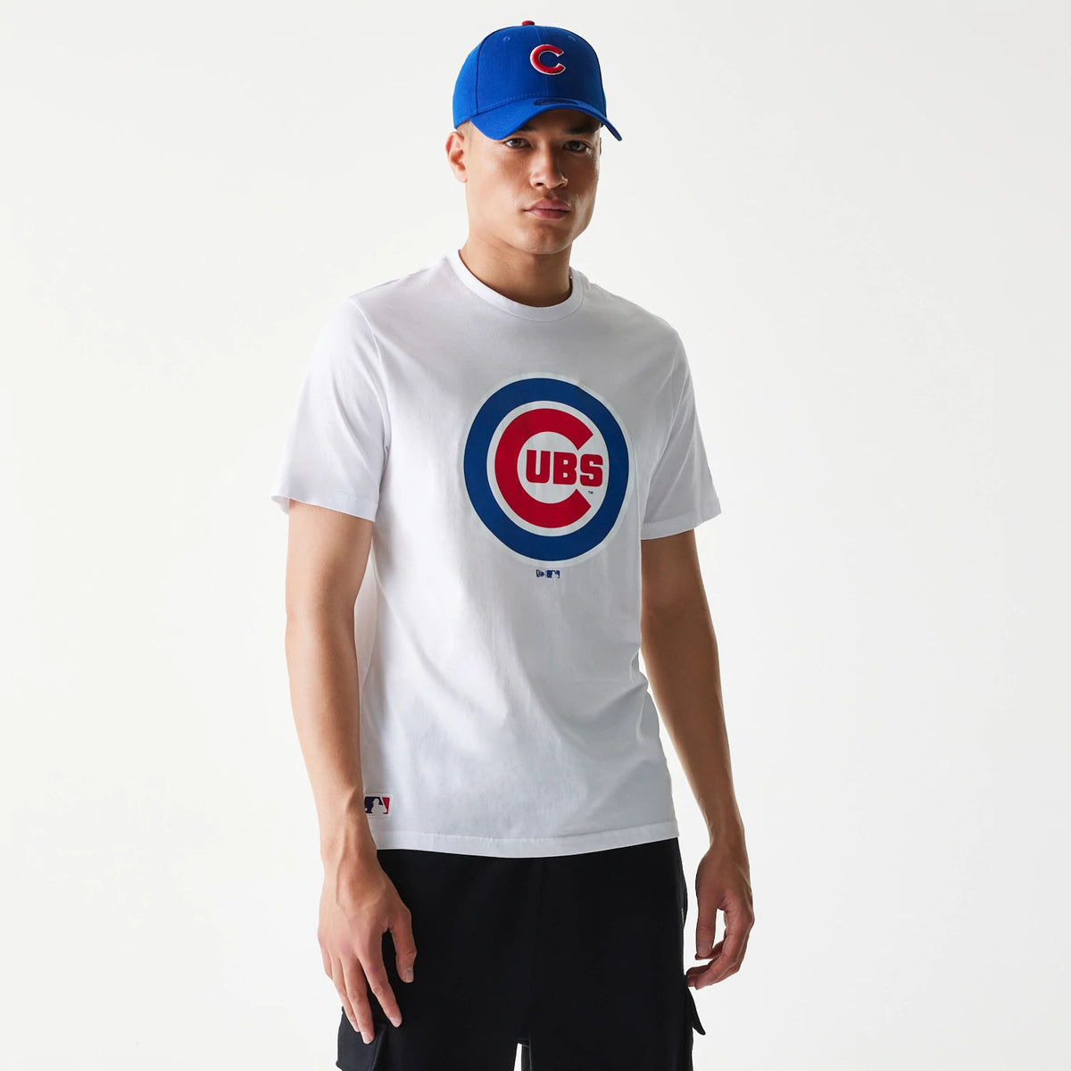 New Era Chicago Cubs MLB Regular White T-Shirt, on-model front view showing a large blue and red Cubs logo centred on the chest, with a small MLB Batterman logo above the hem on the left and a blue cap featuring a raised red and white logo.