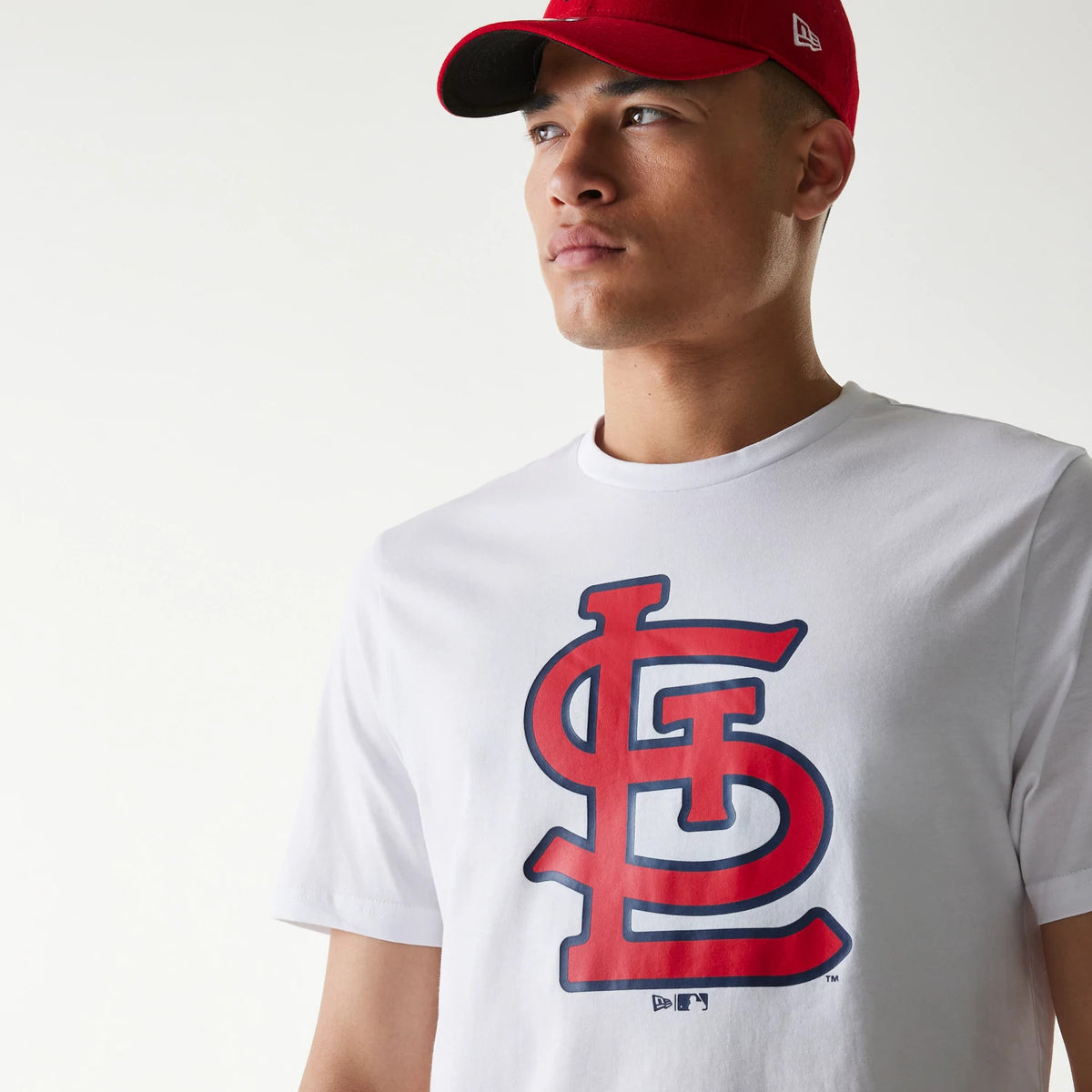 New Era St. Louis Cardinals MLB Regular White T-Shirt, front view featuring a large red and blue STL logo centred on the chest, worn by a person in a red cap with a raised New Era logo on the side.